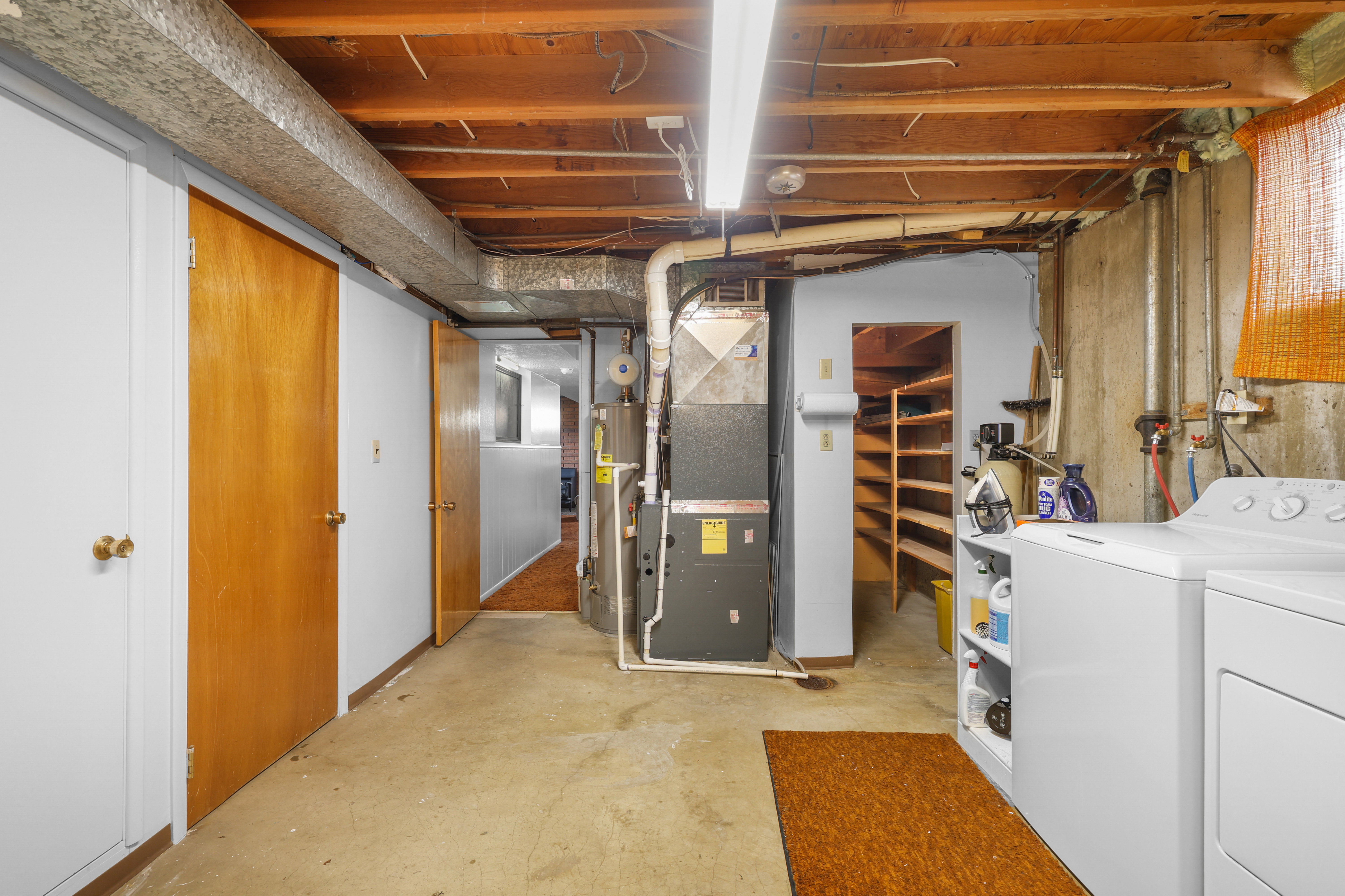 Basement utility area featuring concrete flooring, exposed ceiling joists, and ductwork