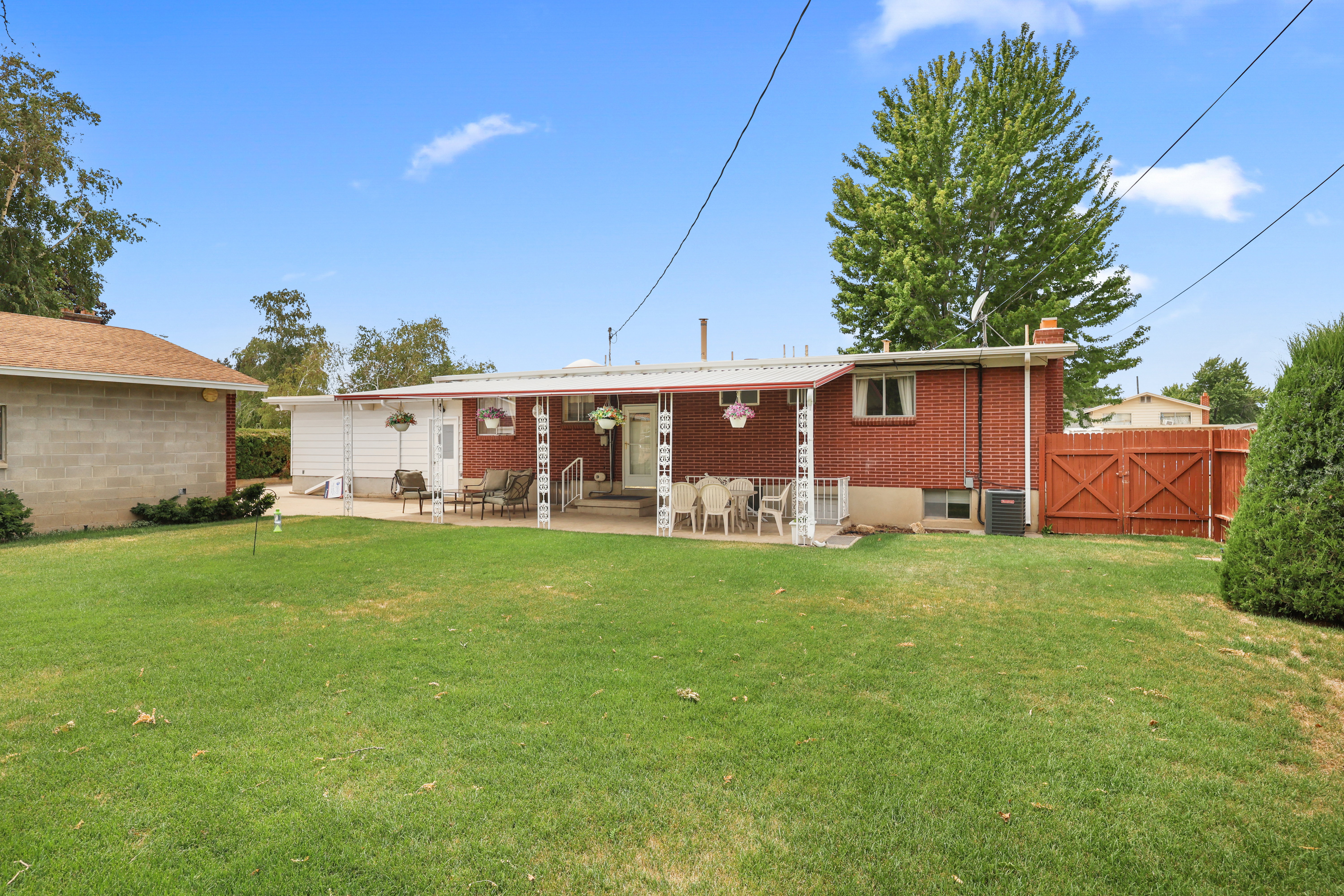 Expansive backyard featuring a red brick exterior, a covered patio, and a privacy fence