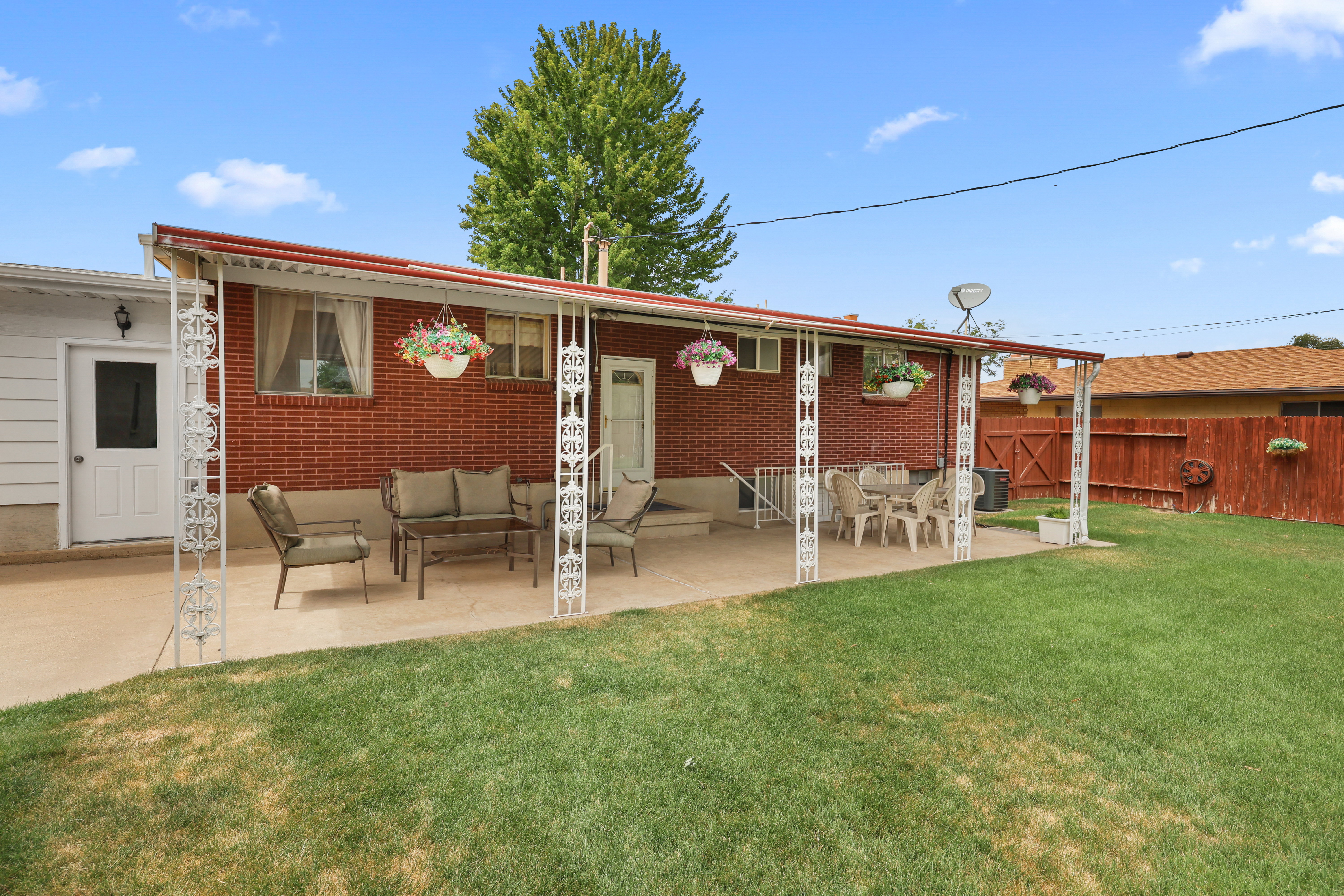 Expansive backyard featuring a covered patio, red brick exterior, and a manicured lawn