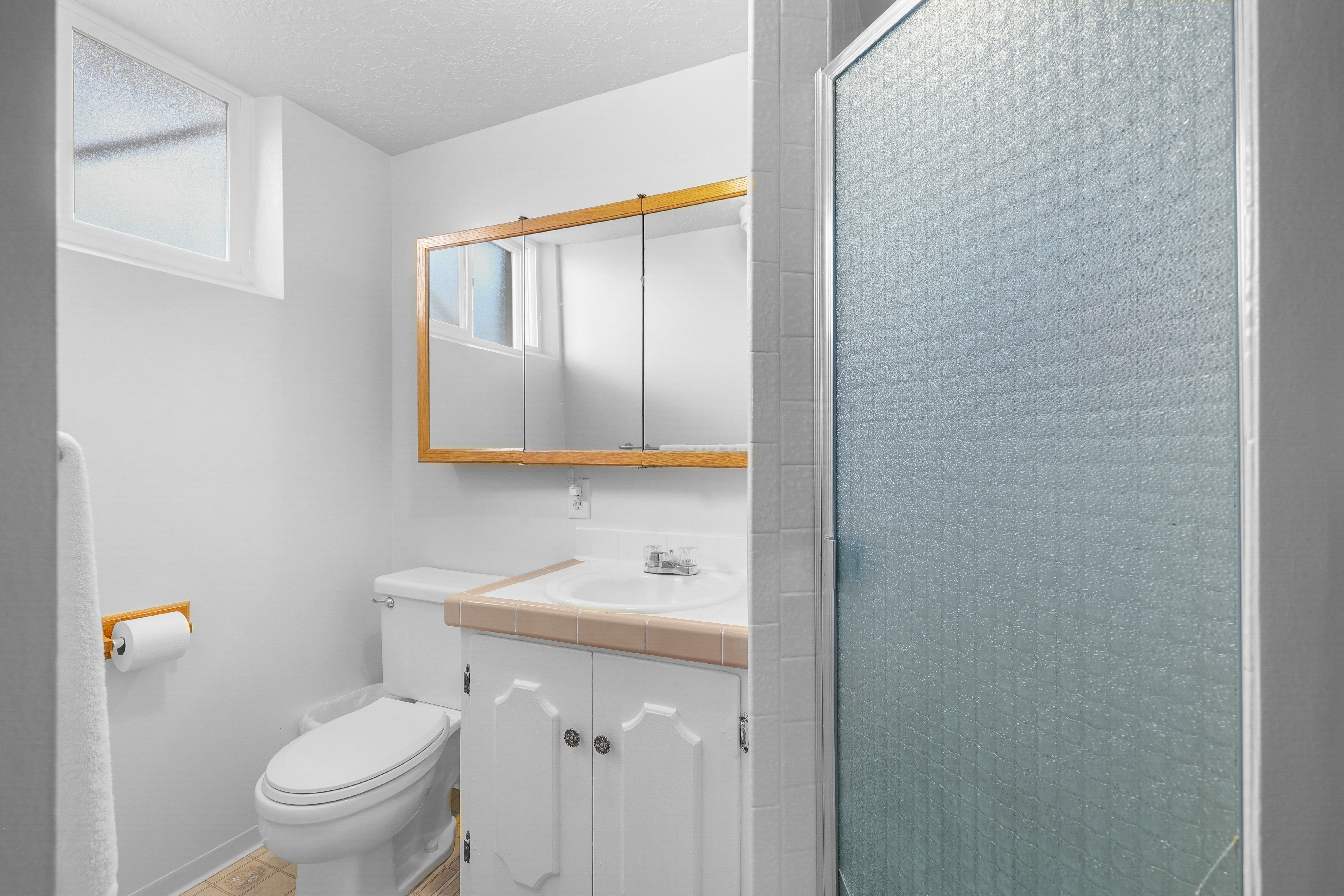 Bathroom featuring a white vanity with decorative cabinet doors, a drop-in sink, and a tiled countertop