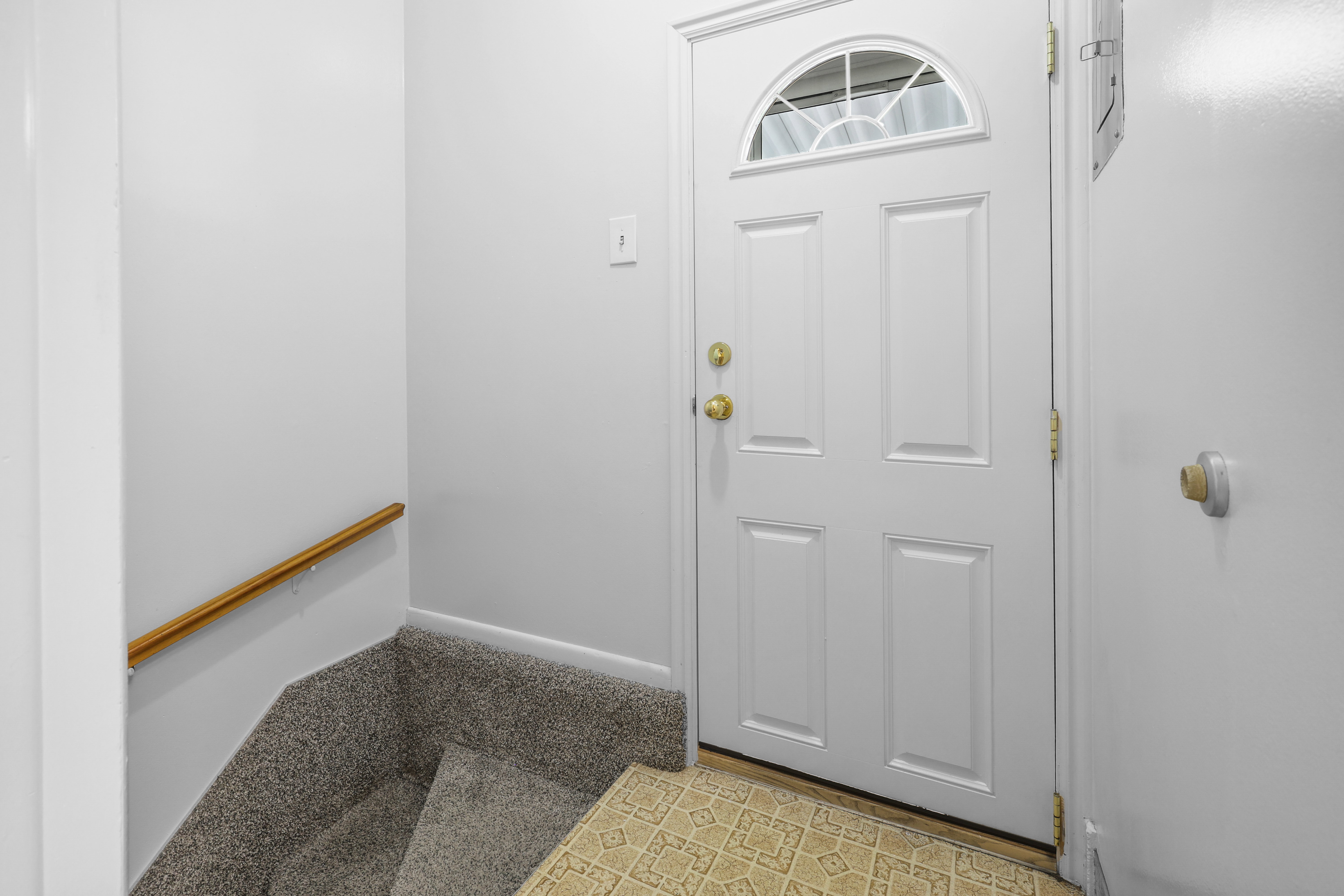 White entry door with an arched transom window and brass hardware