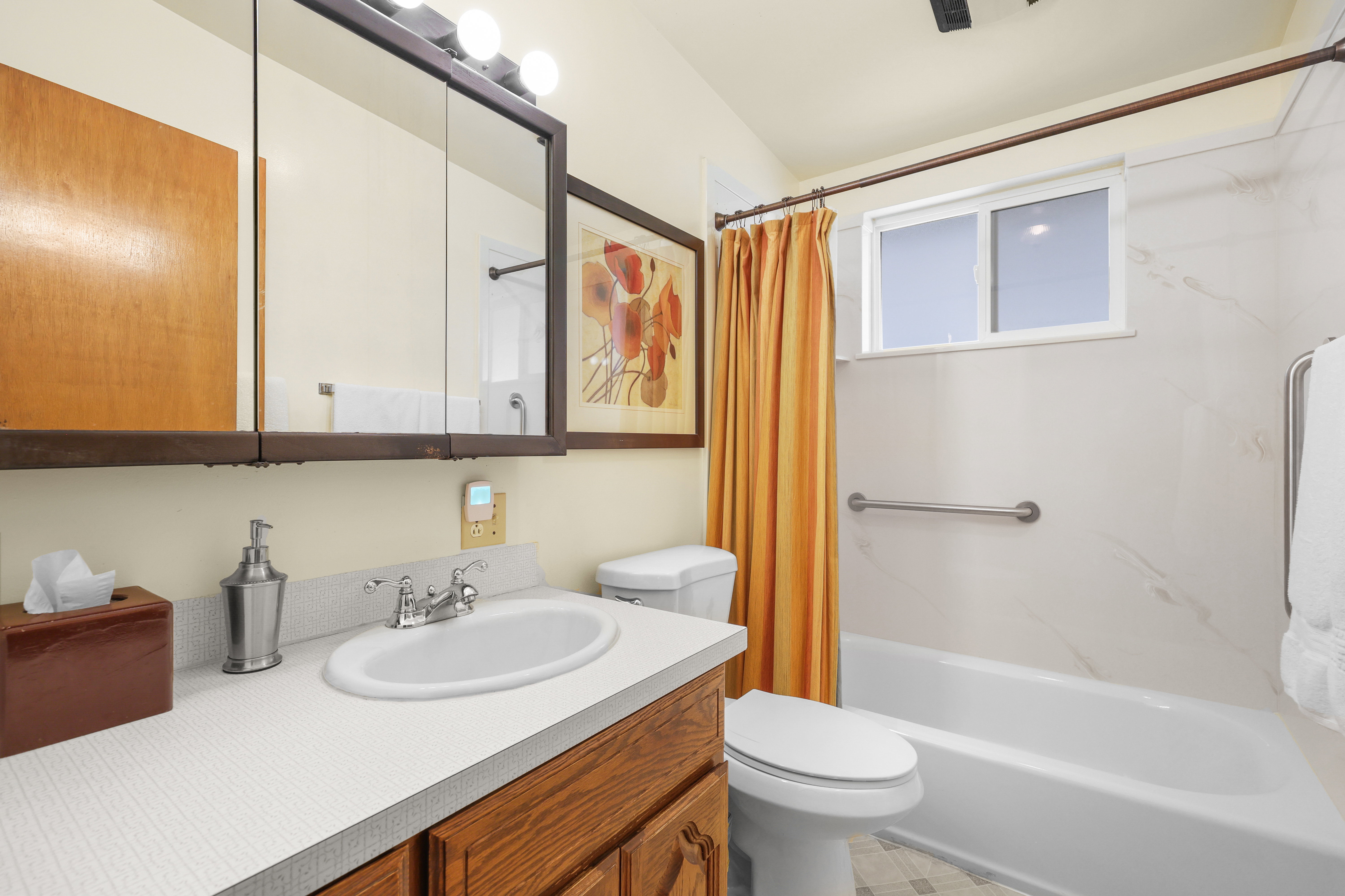 Bathroom featuring a single vanity with wood cabinetry, a laminate countertop, and an integrated sink