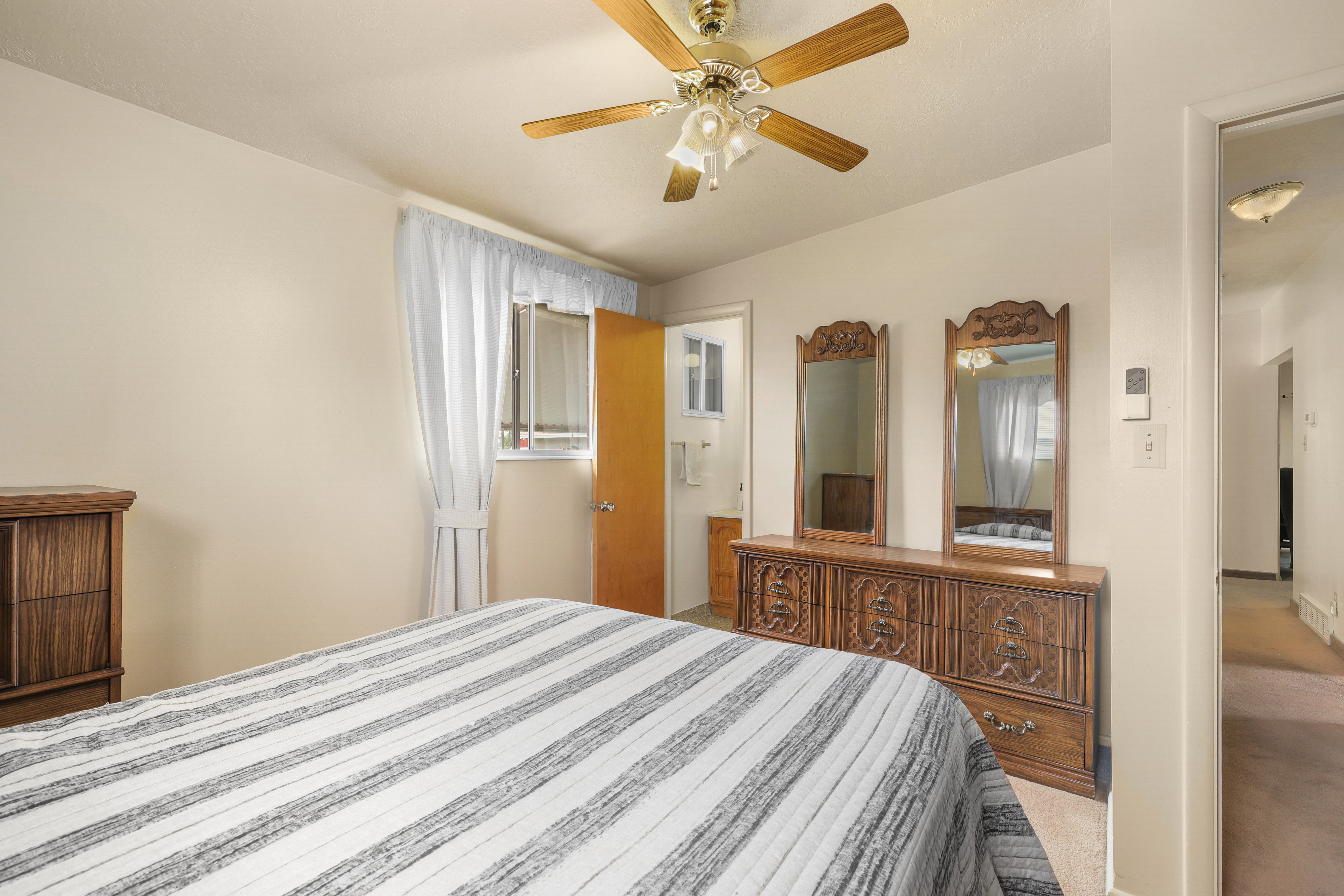 Bedroom with a ceiling fan light fixture, wall-to-wall carpeting, and an adjoining doorway