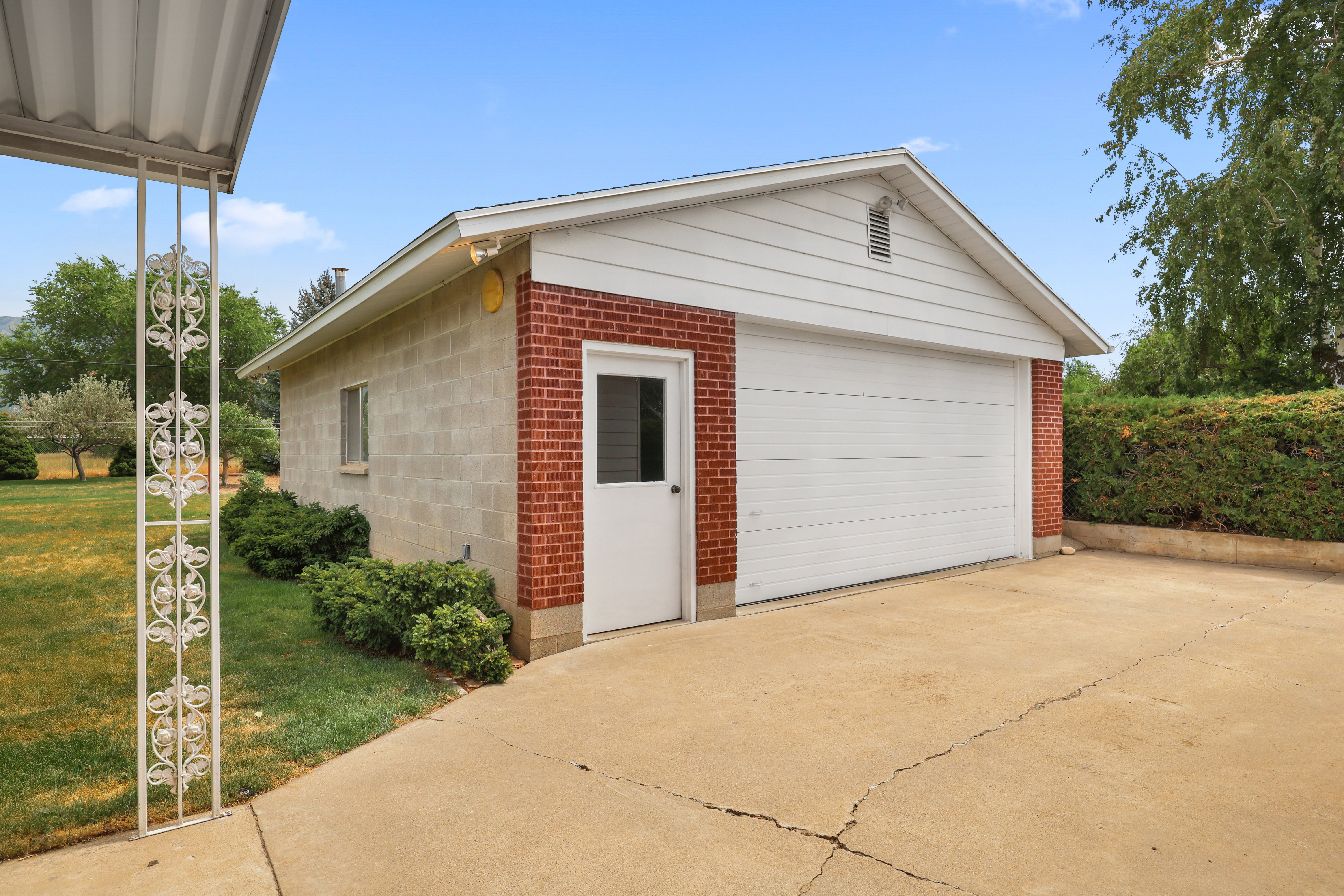 Detached garage featuring brick and concrete block construction, a white overhead door, and a separate service door