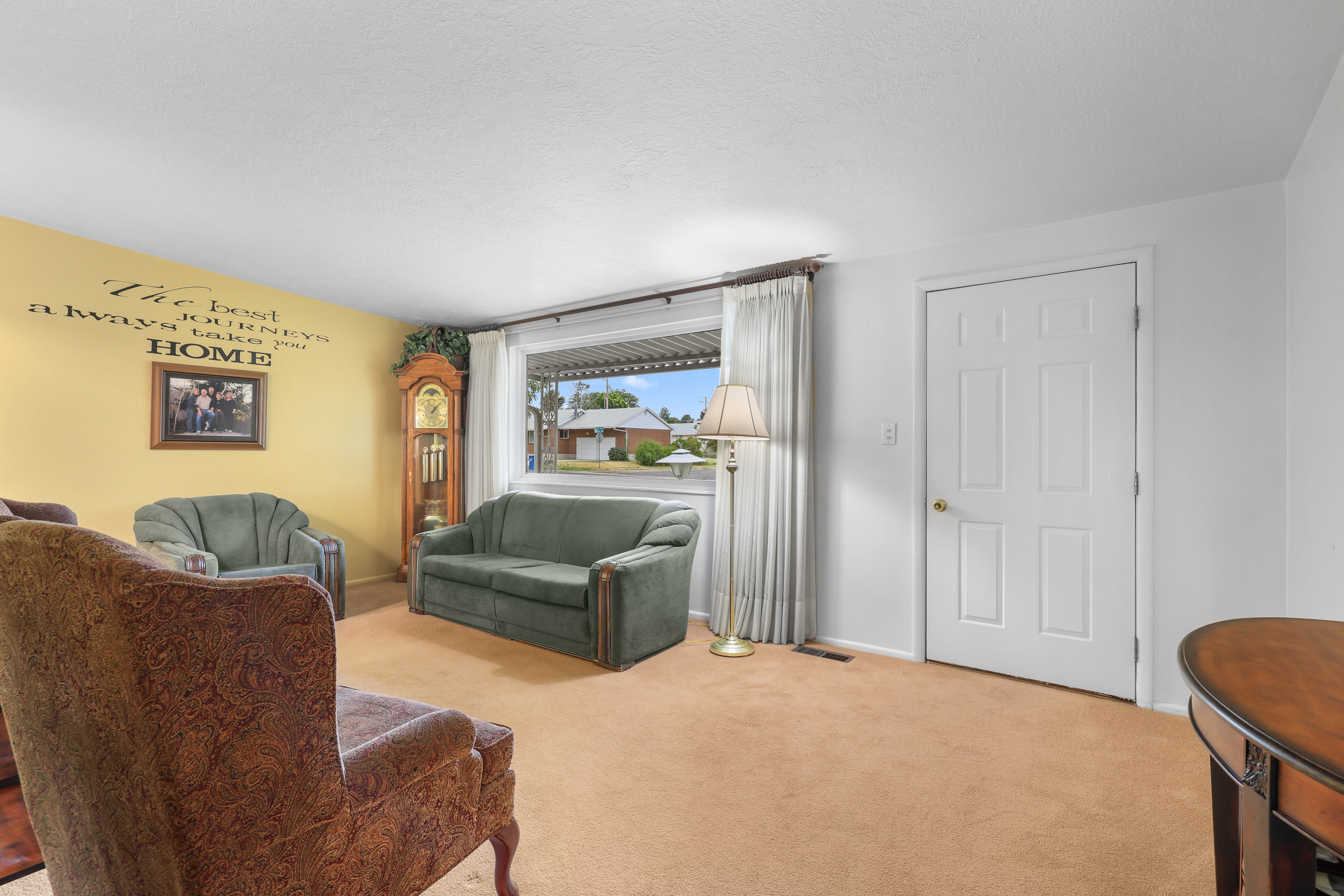 Living area featuring carpeting, a large picture window with drapes, and a paneled interior door