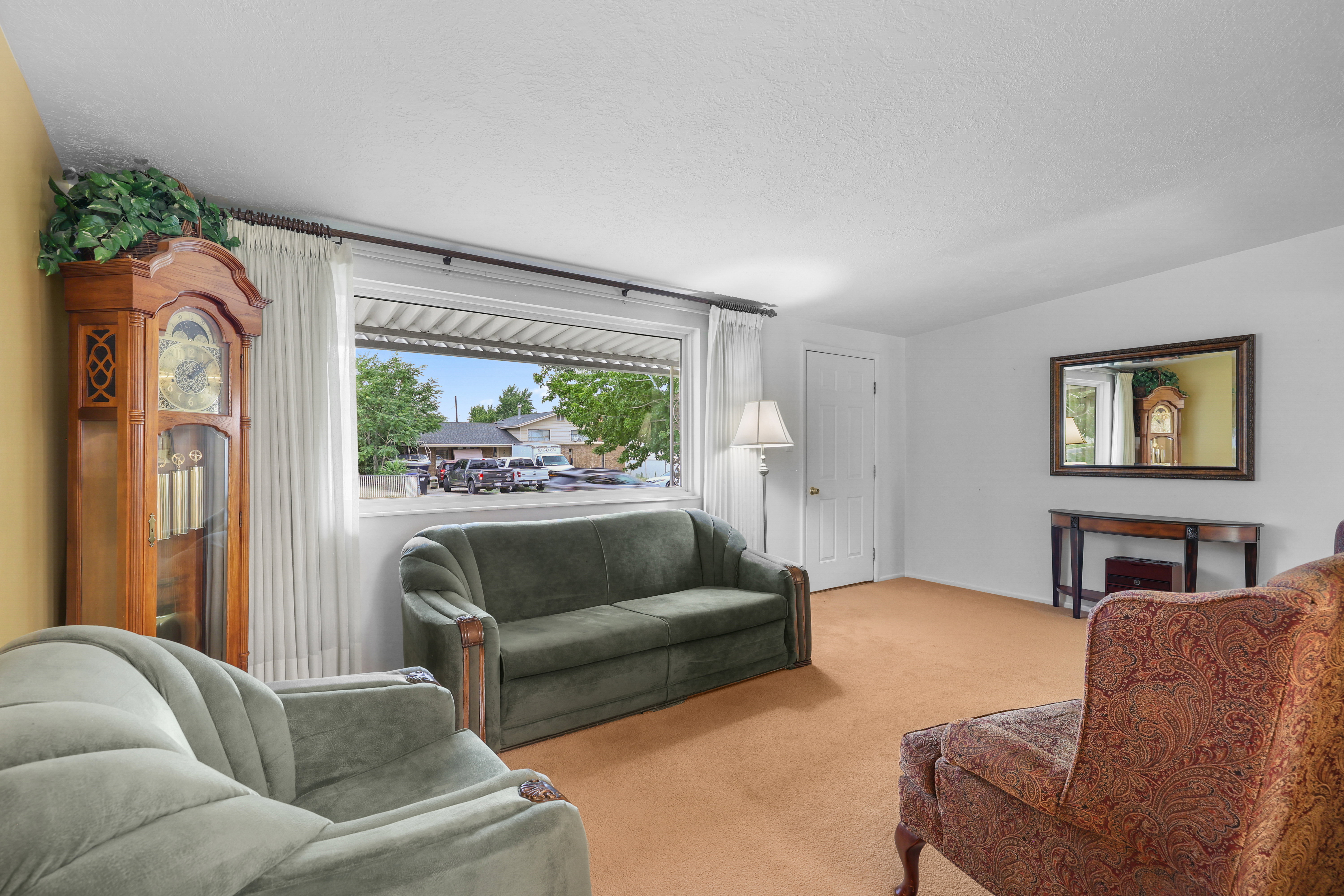 Bright living area featuring a large window, neutral wall paint, and a white paneled door