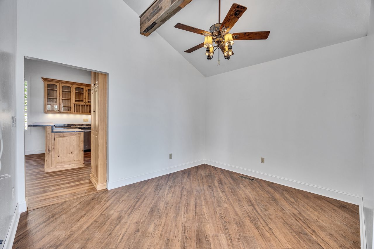 Vaulted ceiling featuring a wood-finish beam and a ceiling fan with integrated lighting