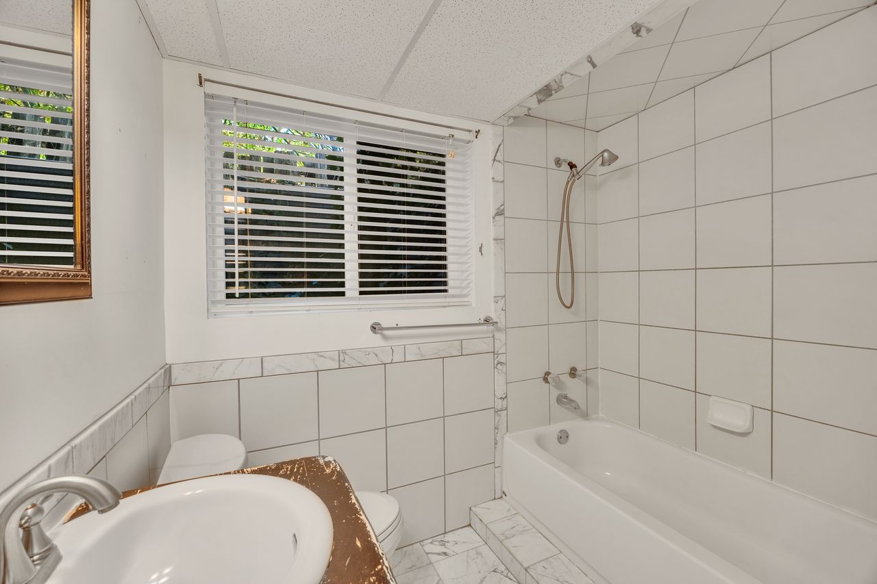 Bathroom featuring a bathtub with shower fixture, white subway tile surround, and an integrated soap dish