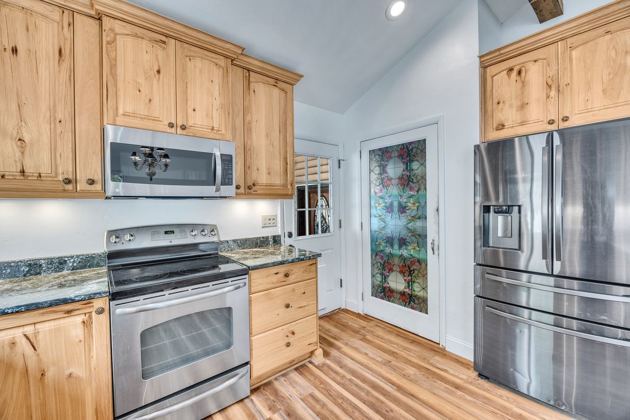 Light wood cabinetry with integrated stainless steel appliances, including a microwave and refrigerator