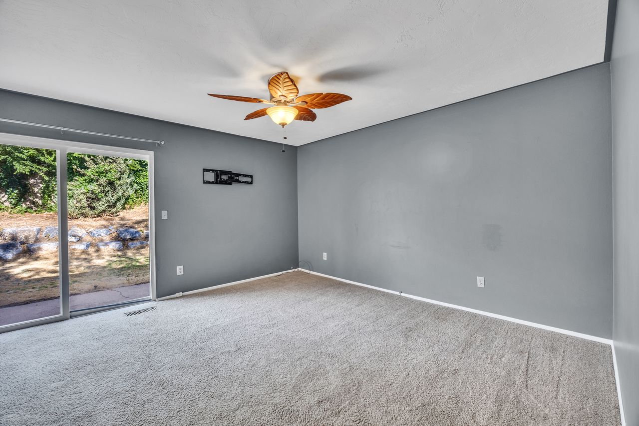 Carpeted Primary bedroom with grey walls and a ceiling fan