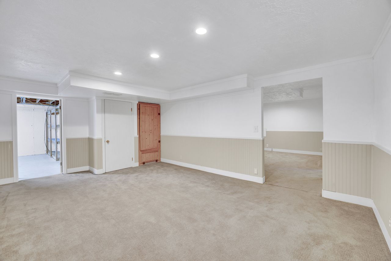 Expansive carpeted area featuring recessed lighting, crown molding, and two-tone walls with beadboard paneling