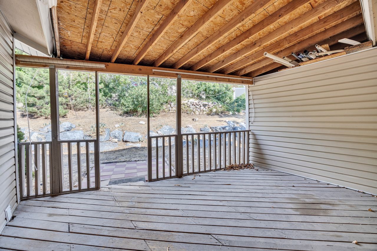 Screened porch with exposed wood ceiling beams, wood plank flooring, and railing