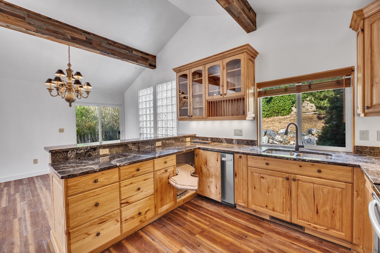 Kitchen featuring extensive wood-finish cabinetry, dark stone countertops, and wood-finish flooring