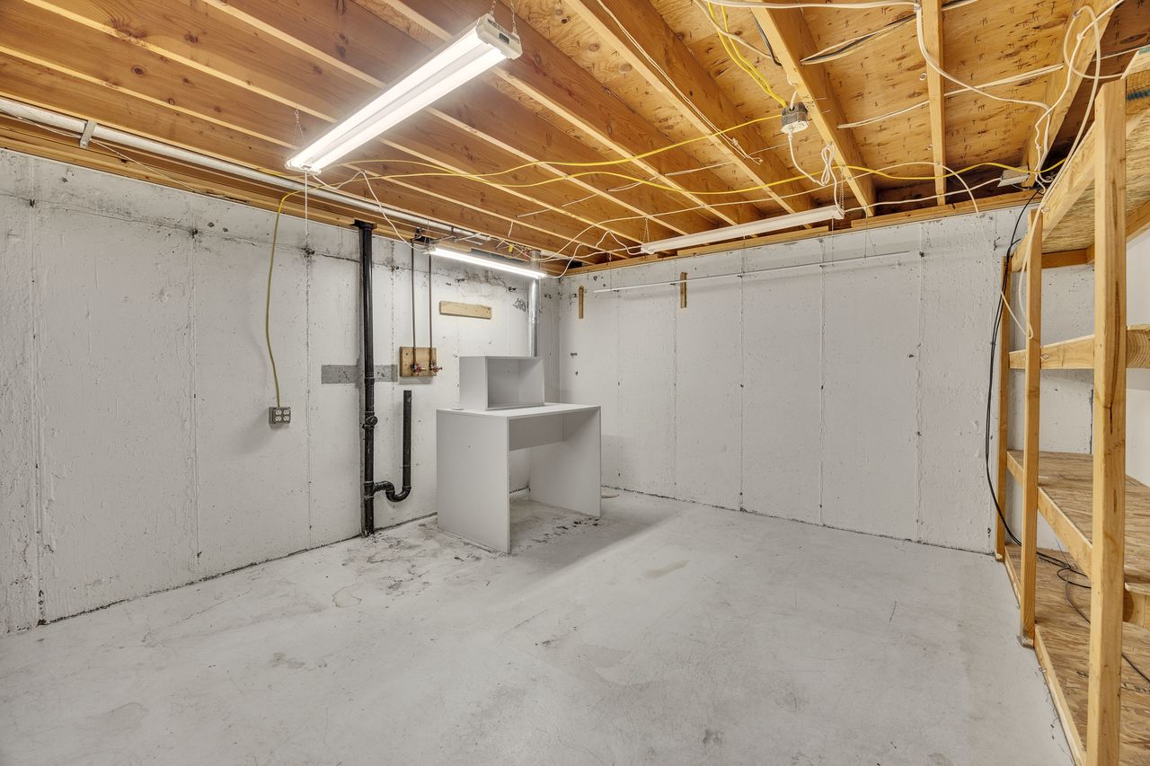 Unfinished basement featuring exposed joists, concrete flooring, and perimeter walls