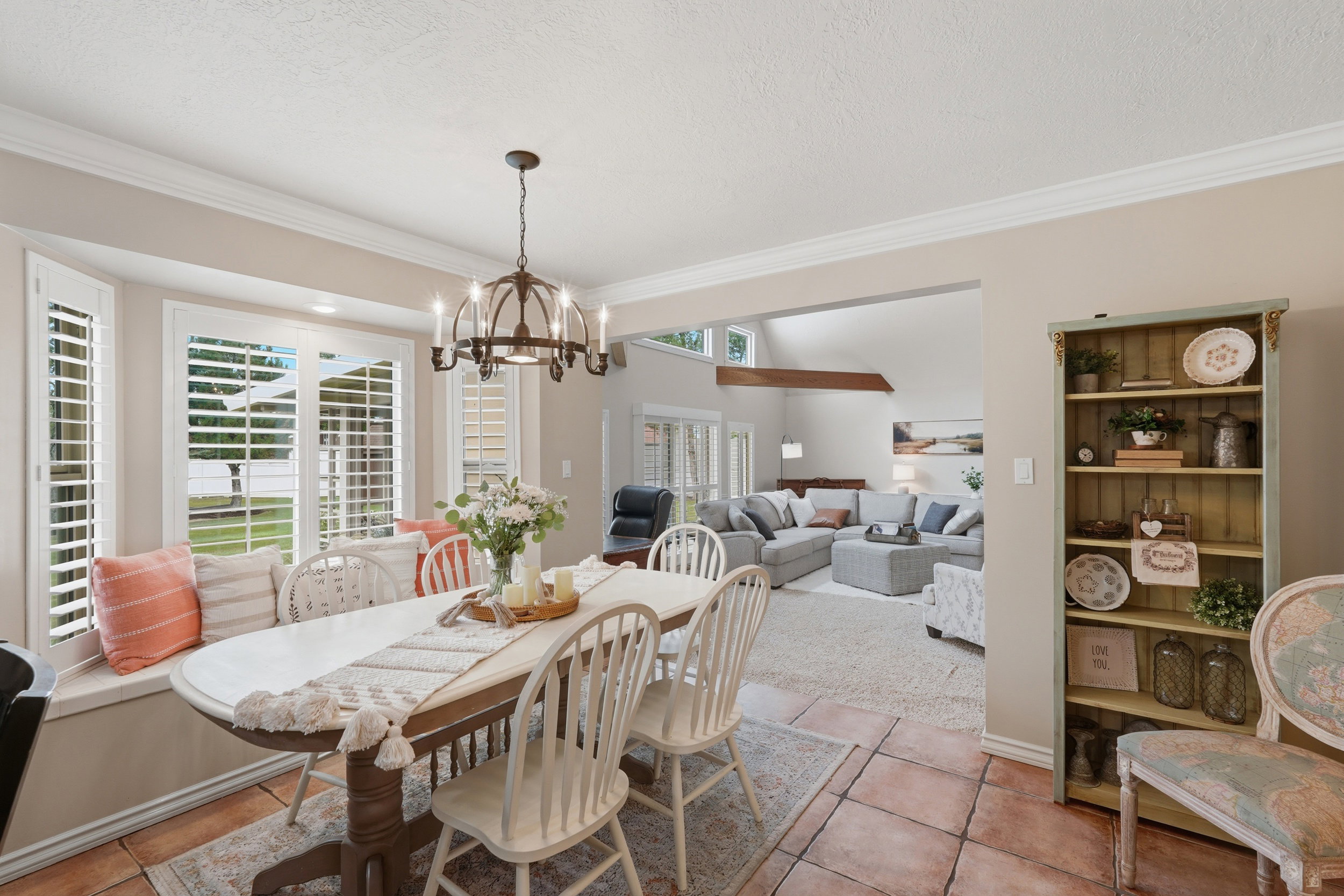 Dining area featuring terracotta-style tile flooring and a bay window with plantation shutters and a built-in window seat