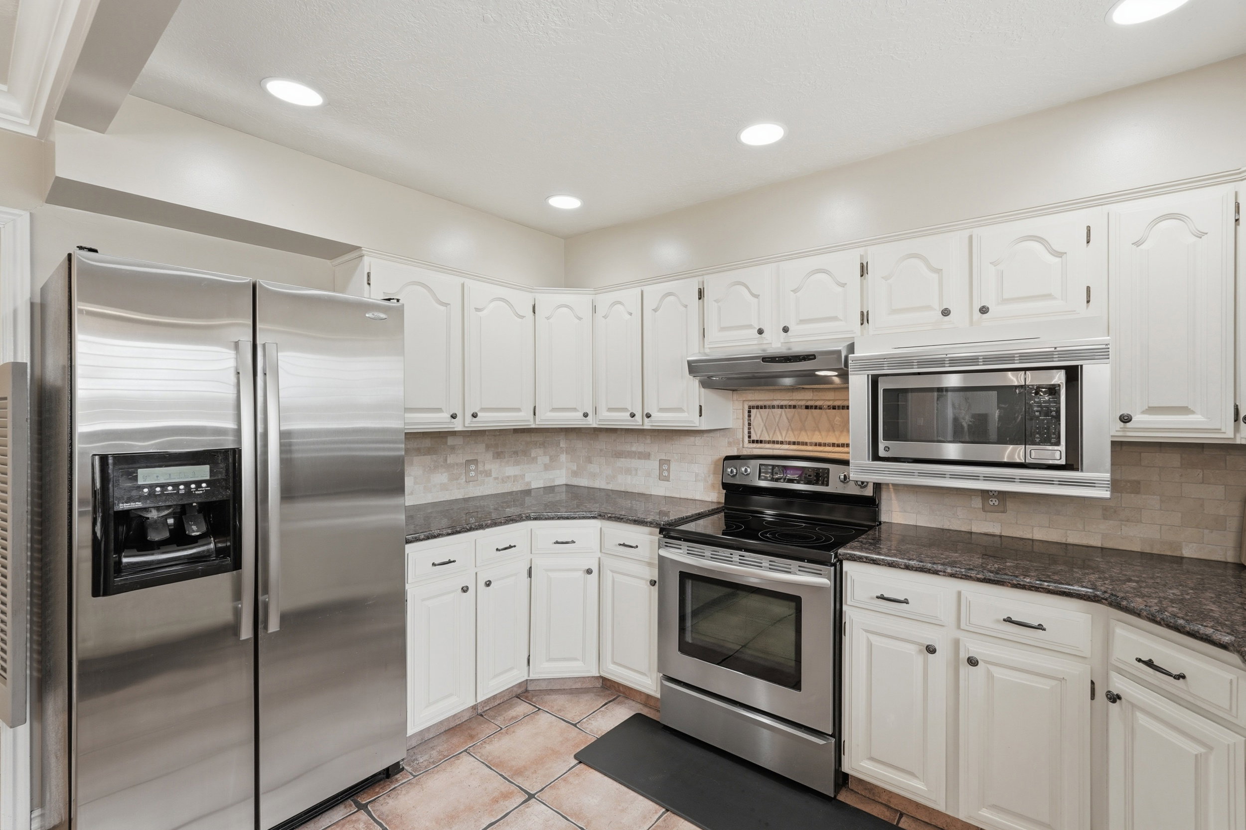 Kitchen featuring white cabinetry, dark countertops, and stainless steel appliances