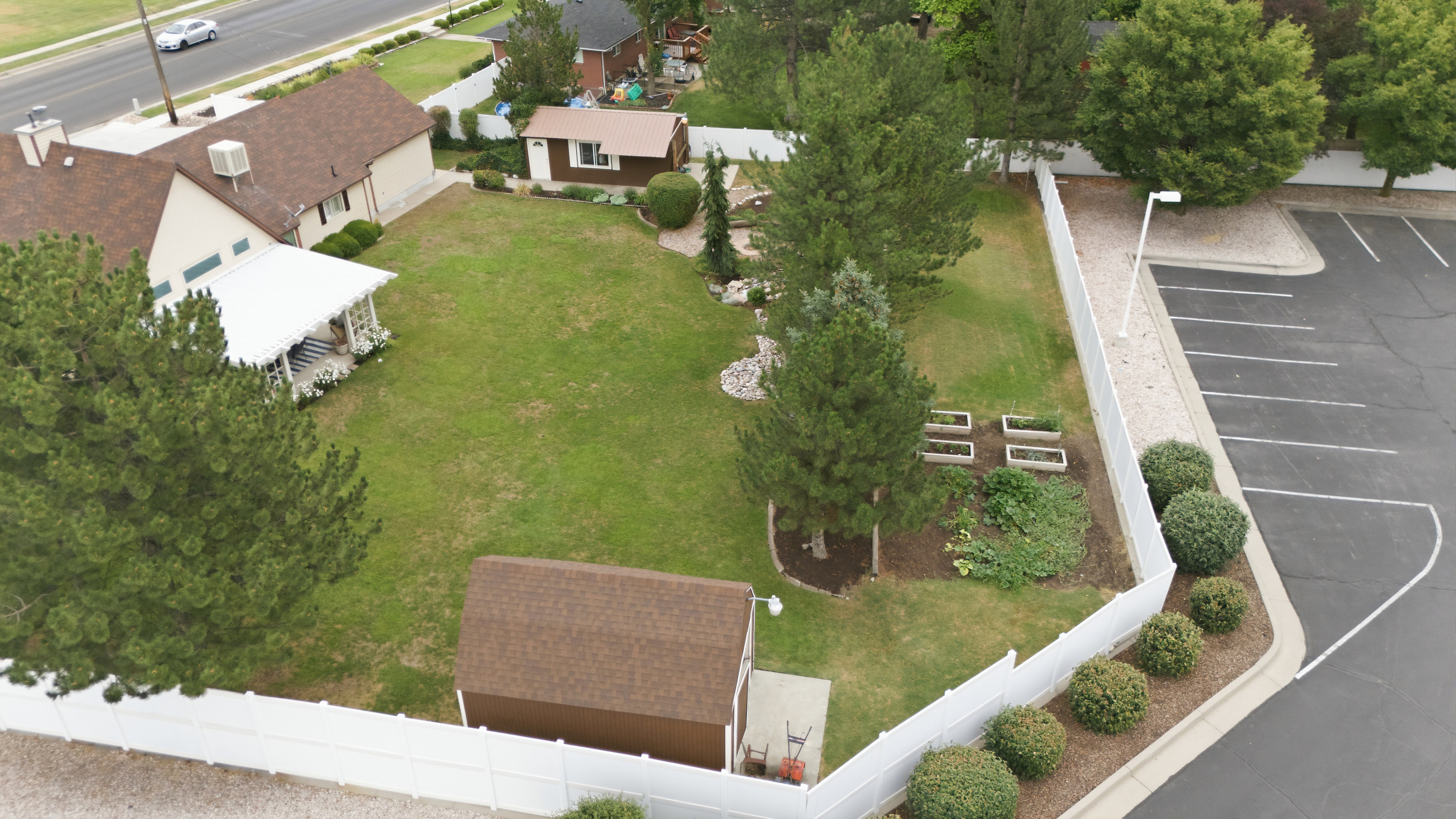 Spacious property featuring a large lawn, mature trees, and a white picket fence
