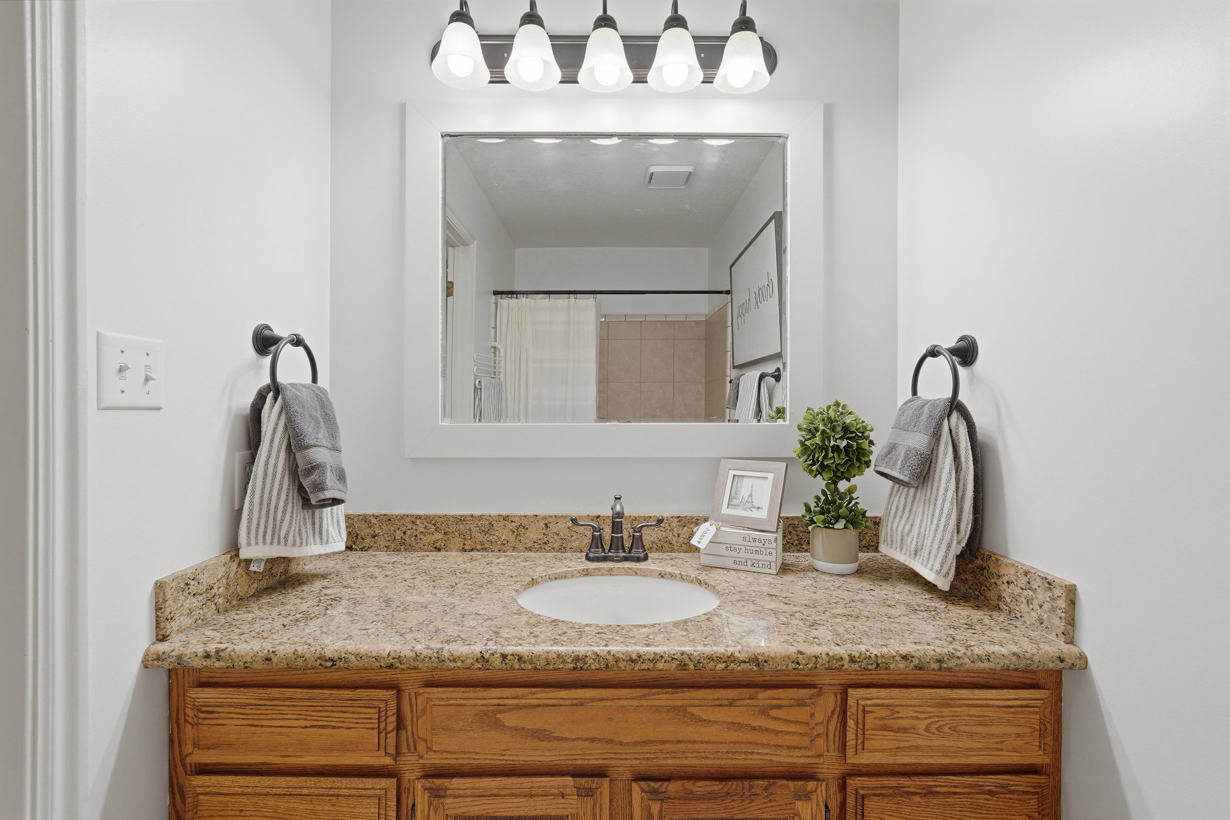 Bathroom vanity featuring a granite countertop with an undermount sink, rich wood cabinetry, and a framed mirror