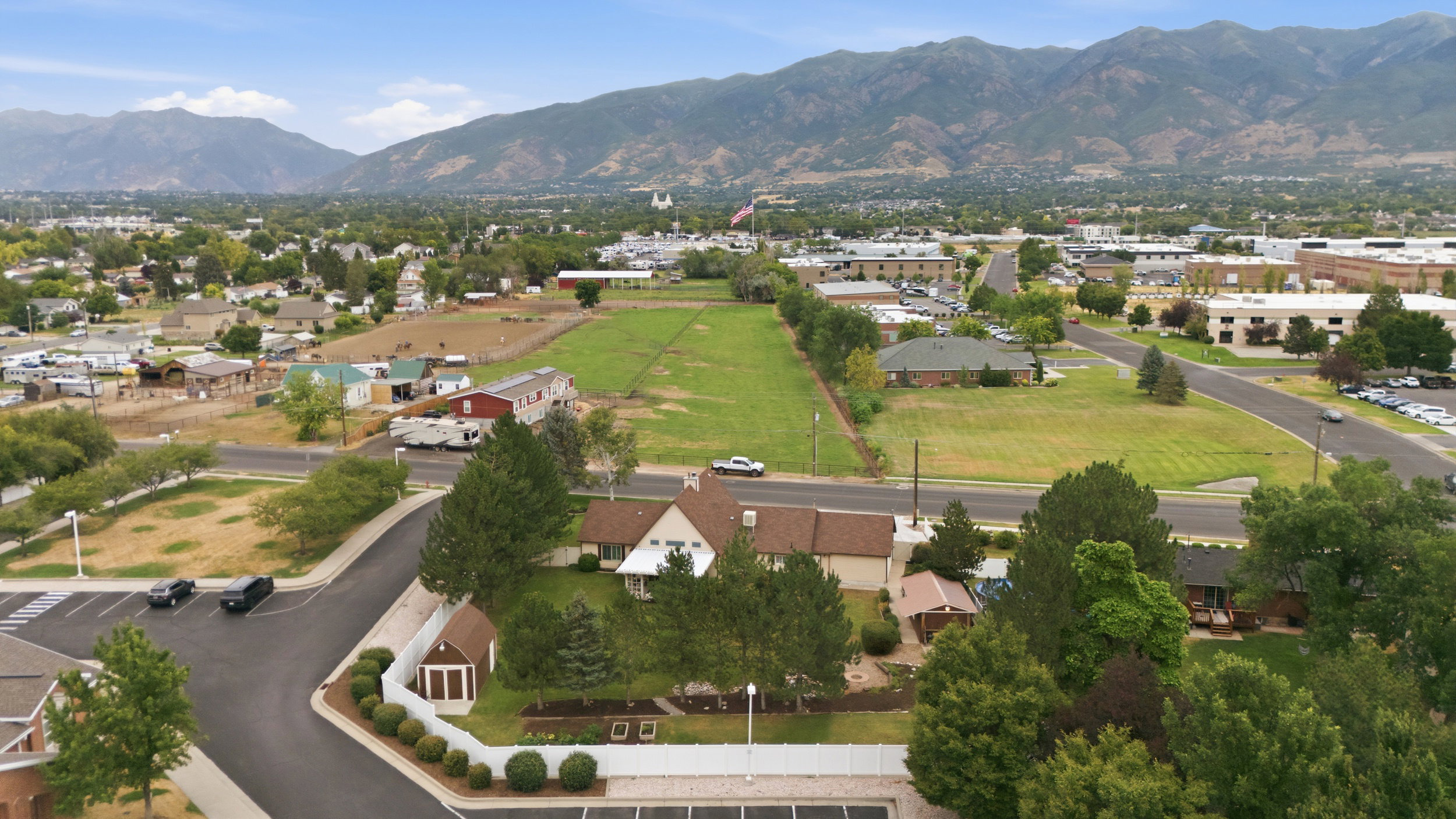 Expansive parcel featuring a large grassy field, bordered by paved roads and mature trees