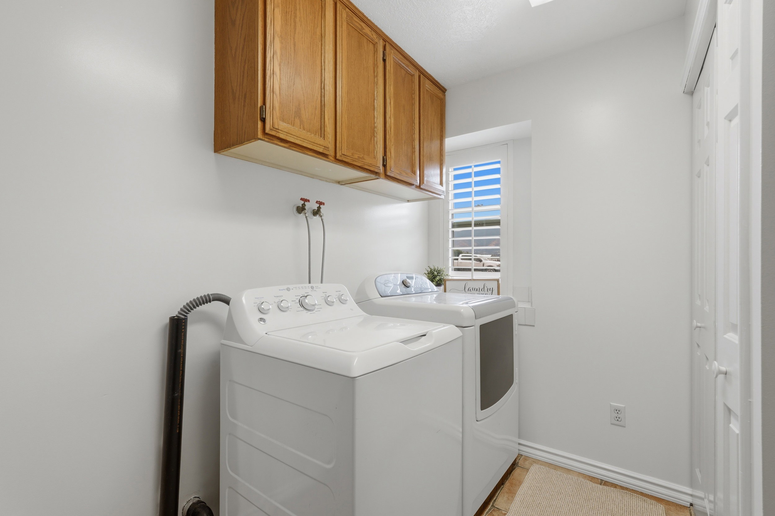 Laundry area featuring overhead wood cabinetry and tile flooring