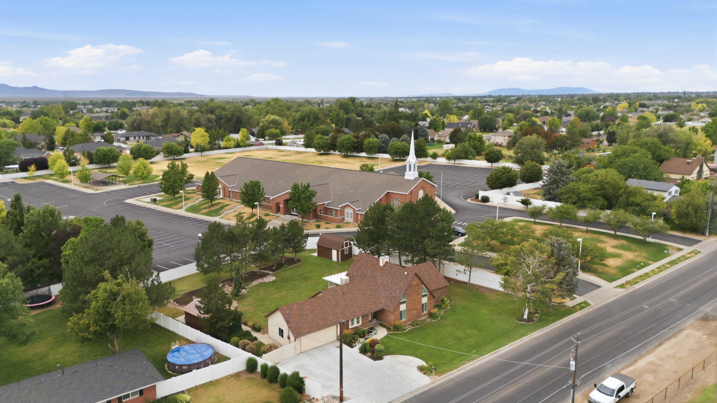 Aerial overview showcasing a residential property with a multi-level brick exterior, an attached garage, and a brown shingle roof