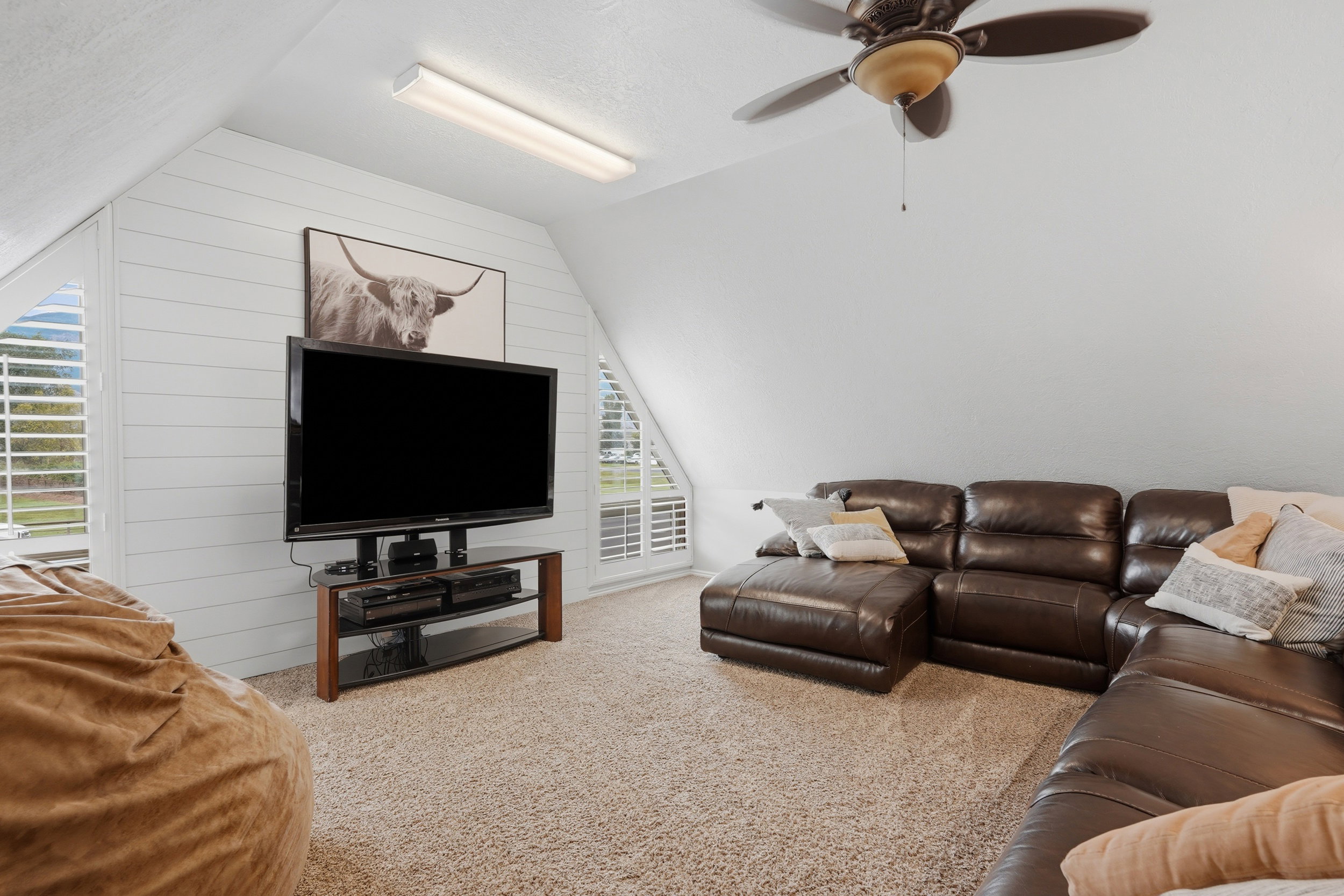 Spacious bonus room featuring an angled ceiling, shiplap accent wall, and textured carpeting