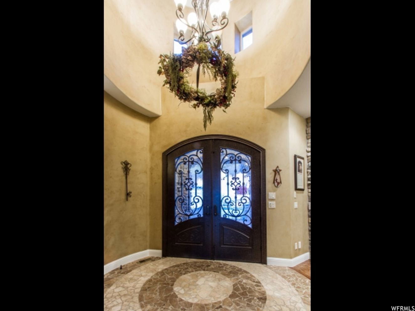 Arched double entry doors featuring decorative wrought iron and glass panels