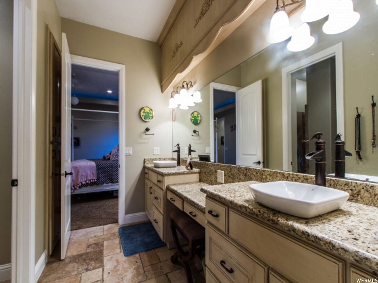 Bathroom featuring a double vanity with granite countertops, vessel sinks, and bronze-finish faucets