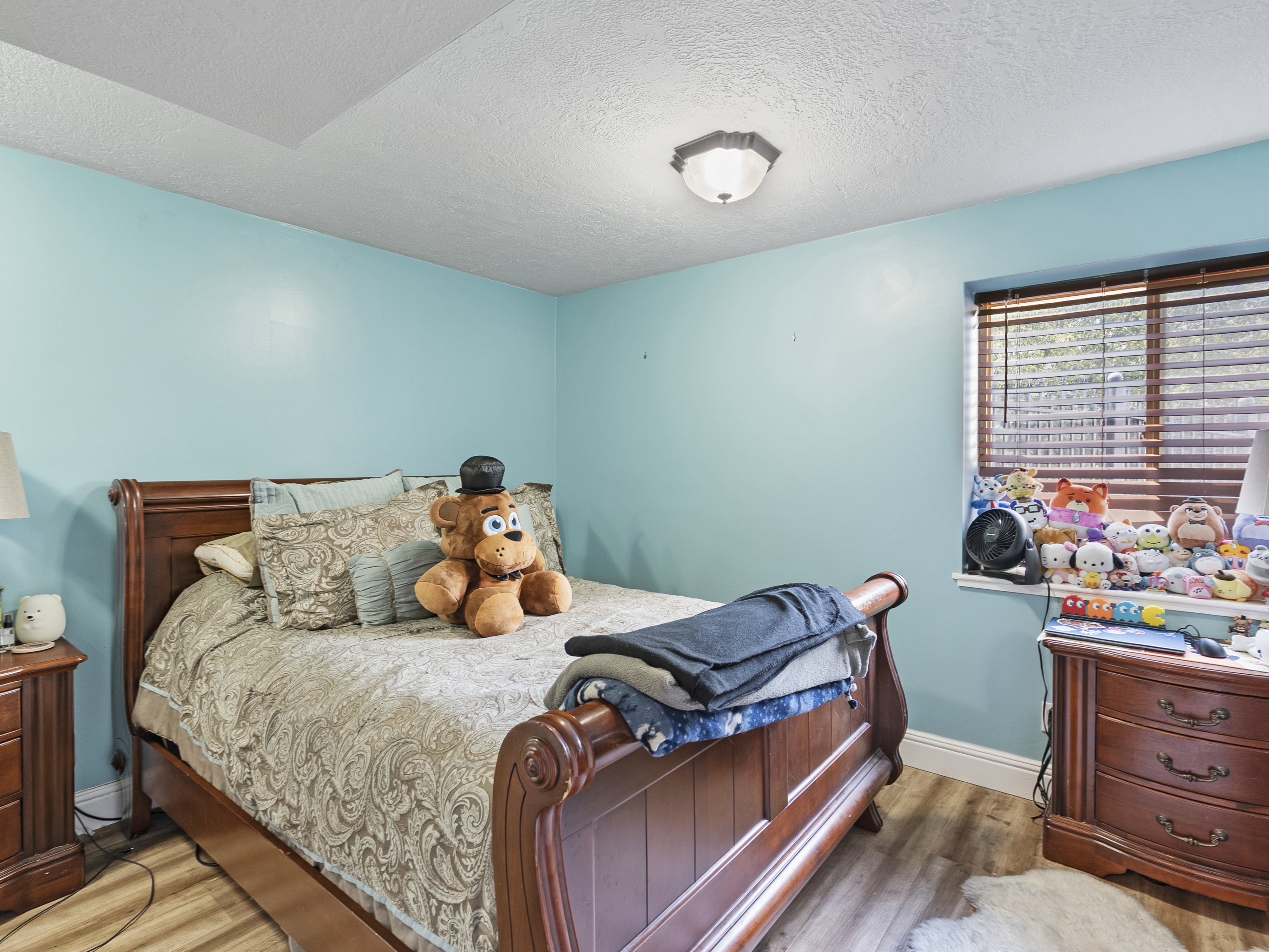 Bedroom featuring wood-finish flooring, a window with wood blinds, and a flush-mount ceiling light