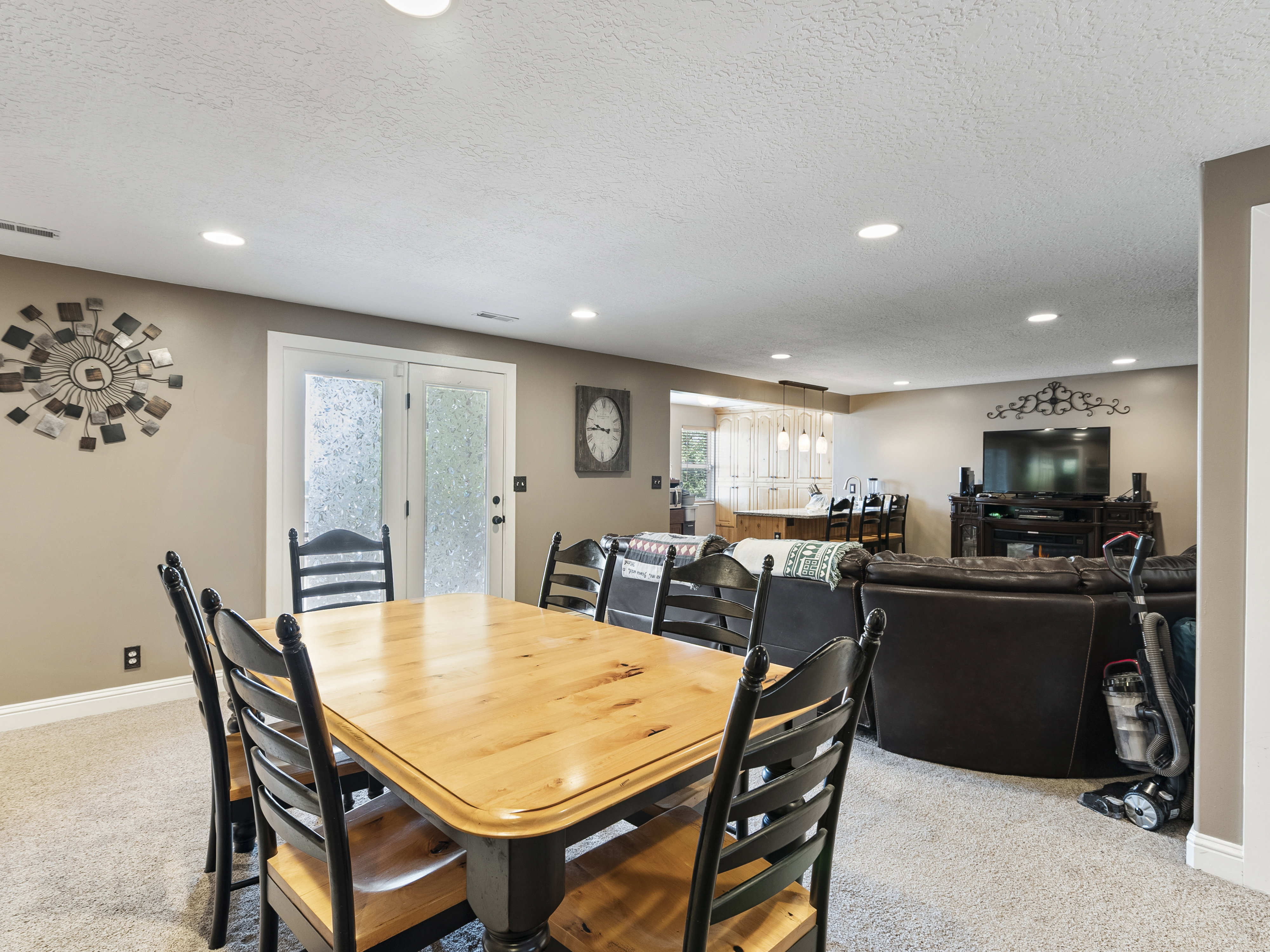 Spacious recreation area featuring recessed lighting, neutral wall tones, textured carpeting, and double glass-paneled doors