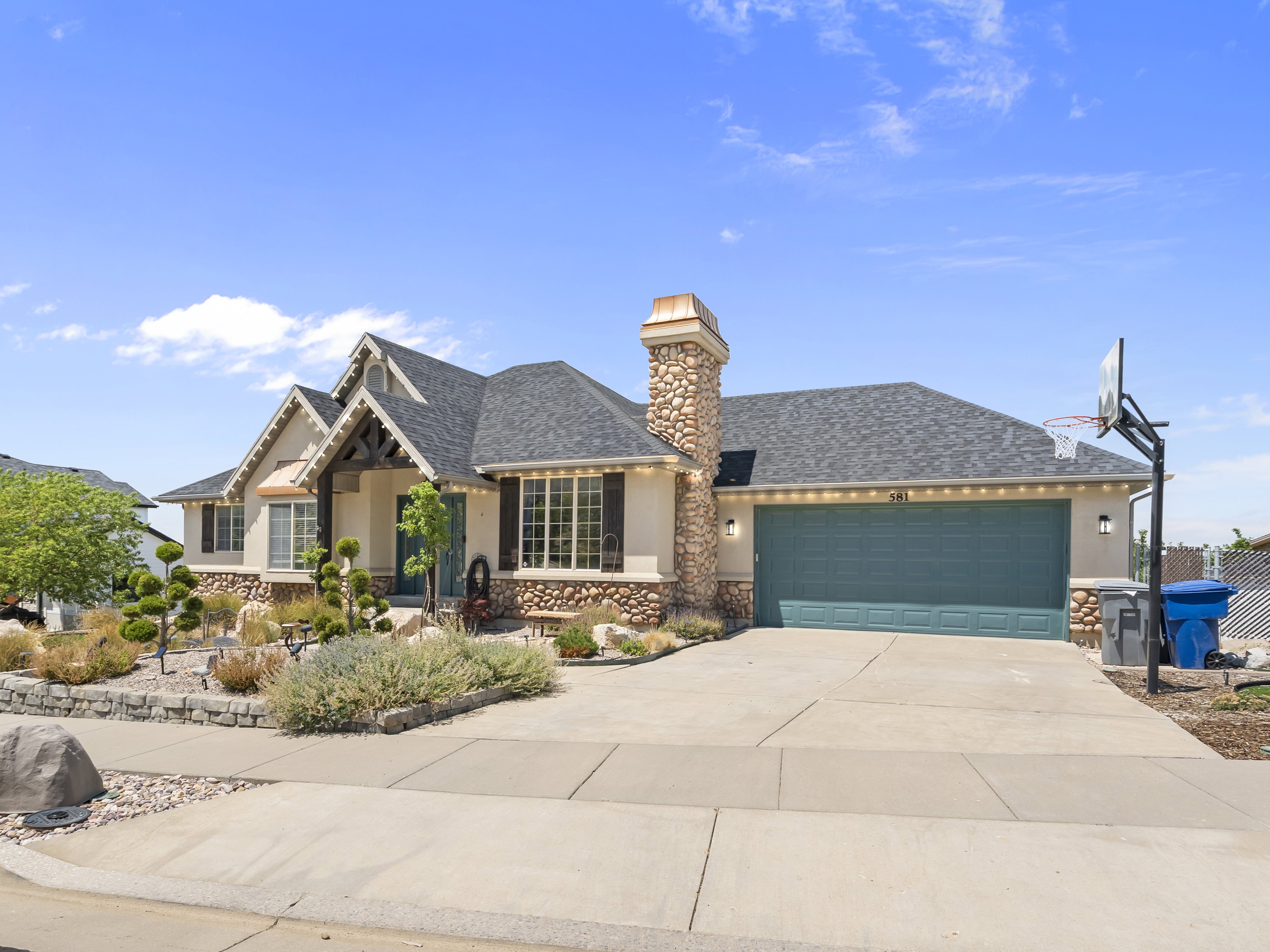 Stone and stucco exterior with a dark shingle roof