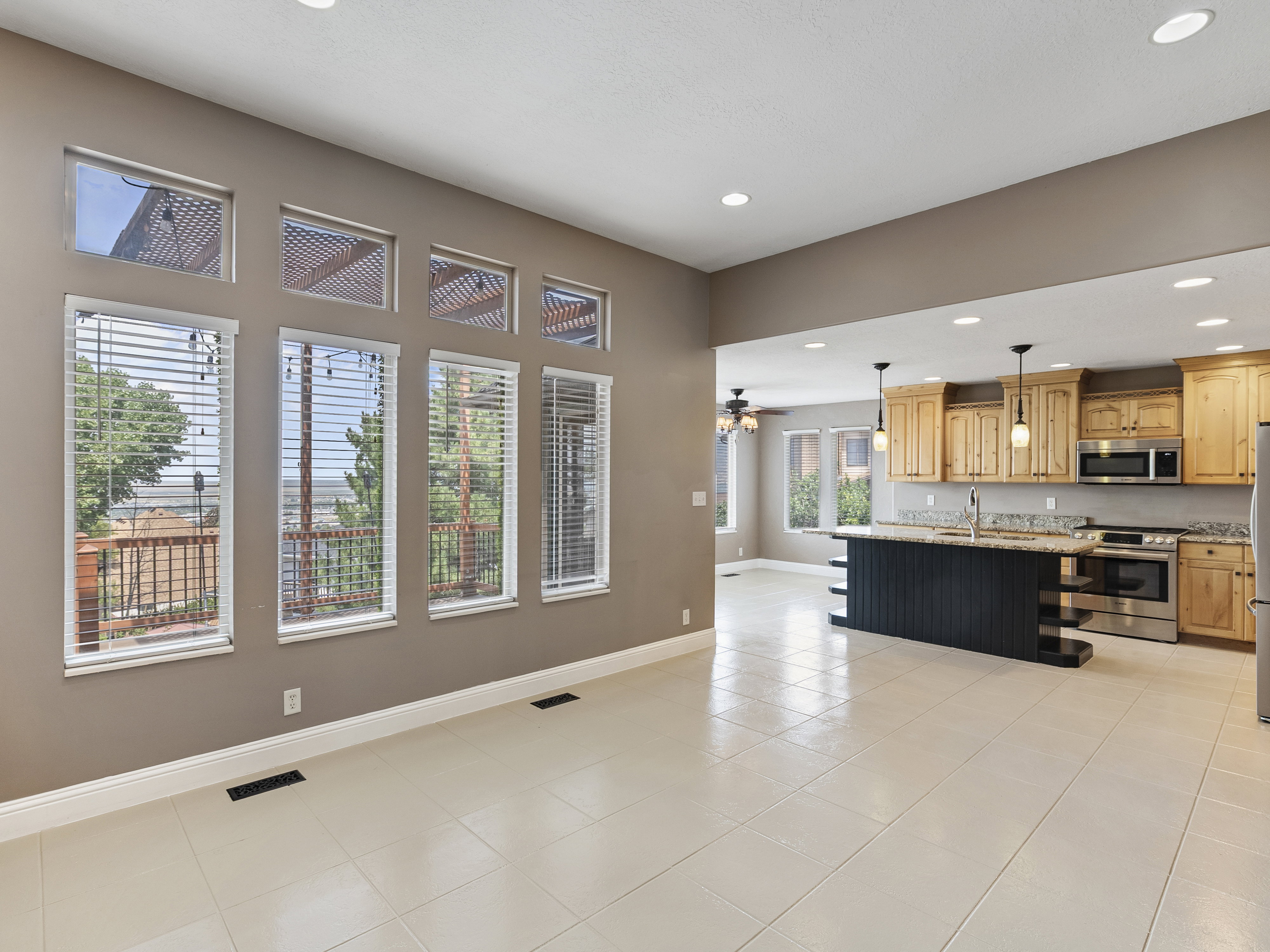 Open-concept living space featuring large windows, a full kitchen, tile flooring, recessed lighting, and a deck