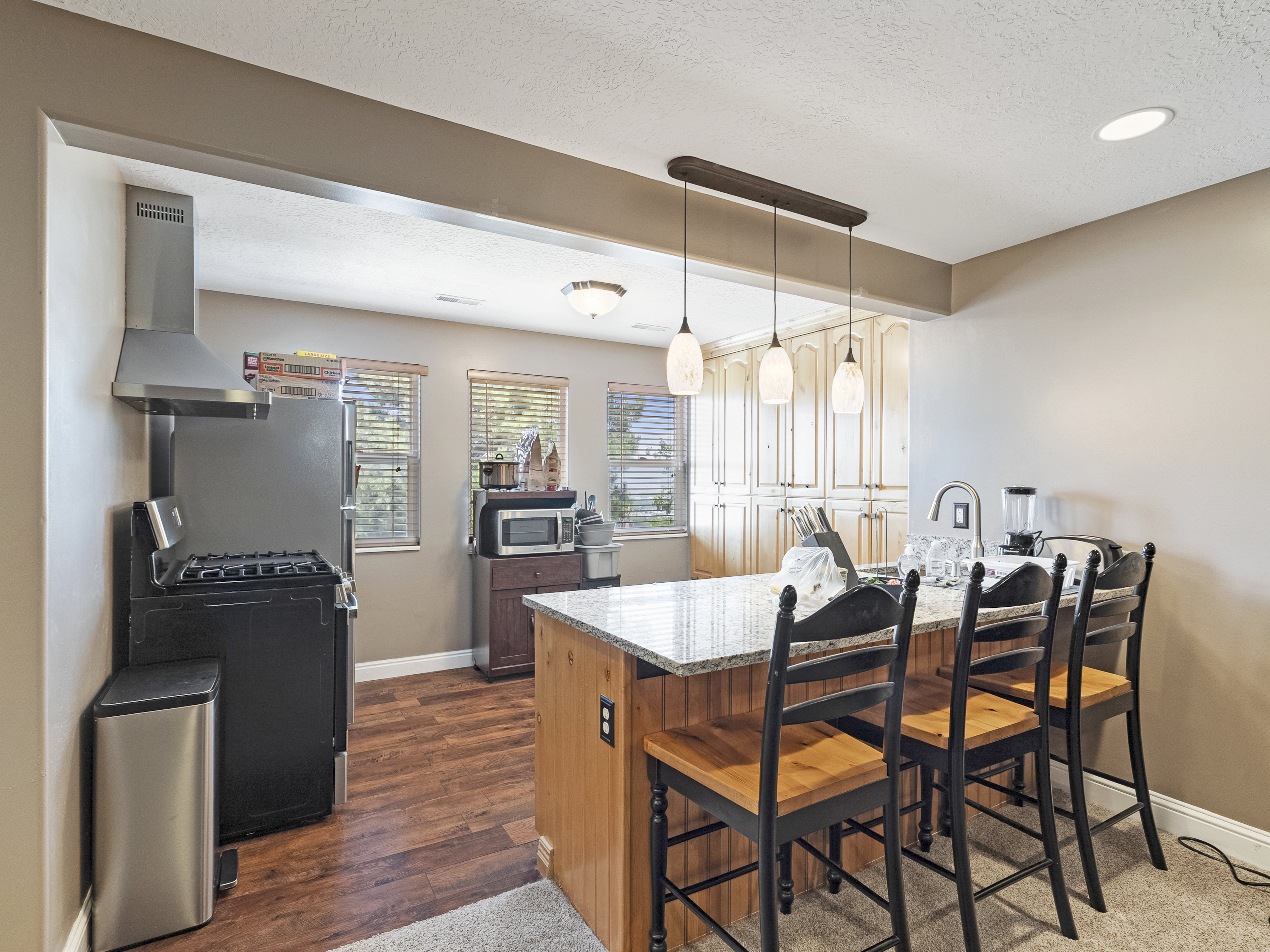 Kitchen featuring a stainless steel range hood, wood-finish flooring, recessed lighting, a kitchen island with seating, and extensive built-in cabinetry