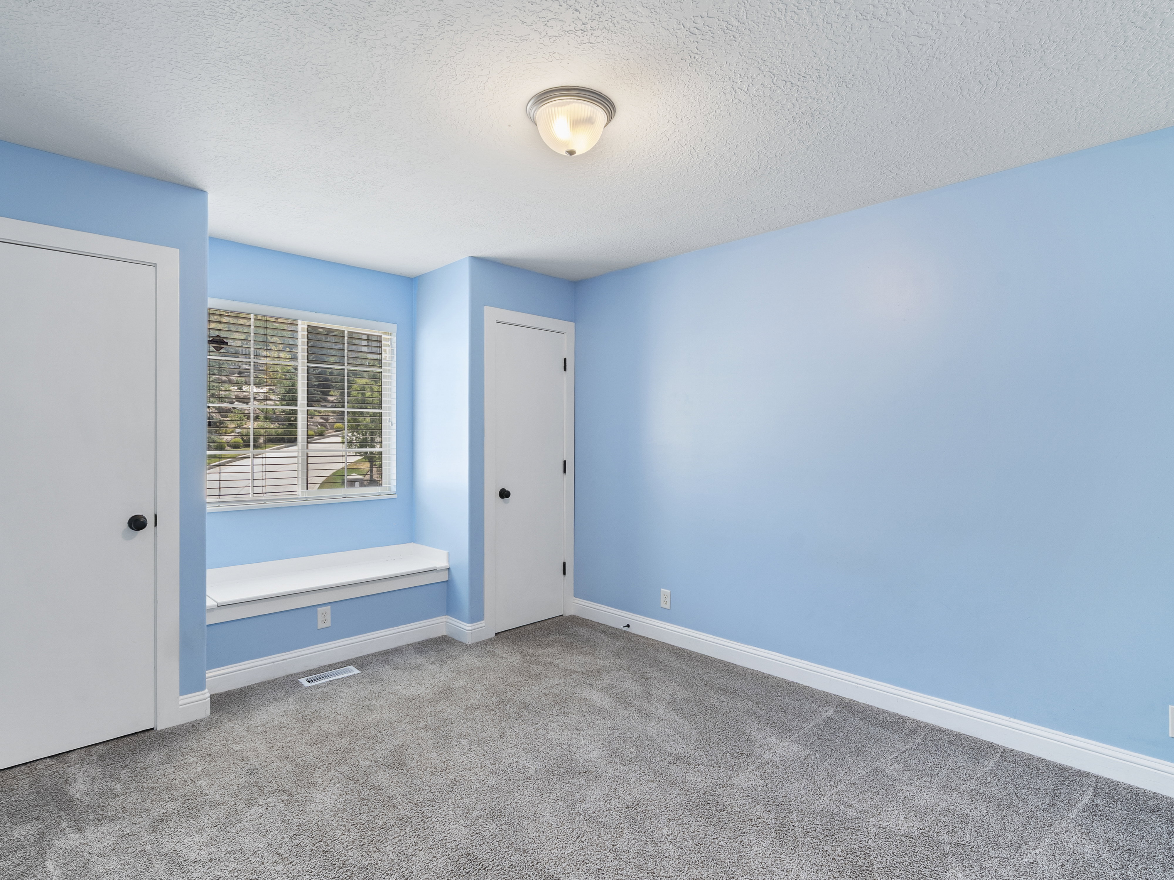 Bedroom featuring a window seat, gray carpeting, and two white paneled doors