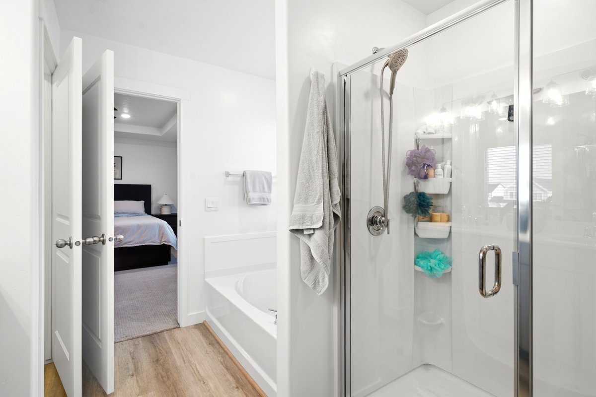 Contemporary bathroom featuring a glass-enclosed shower with a handheld shower fixture, a built-in tub, and wood-finish flooring