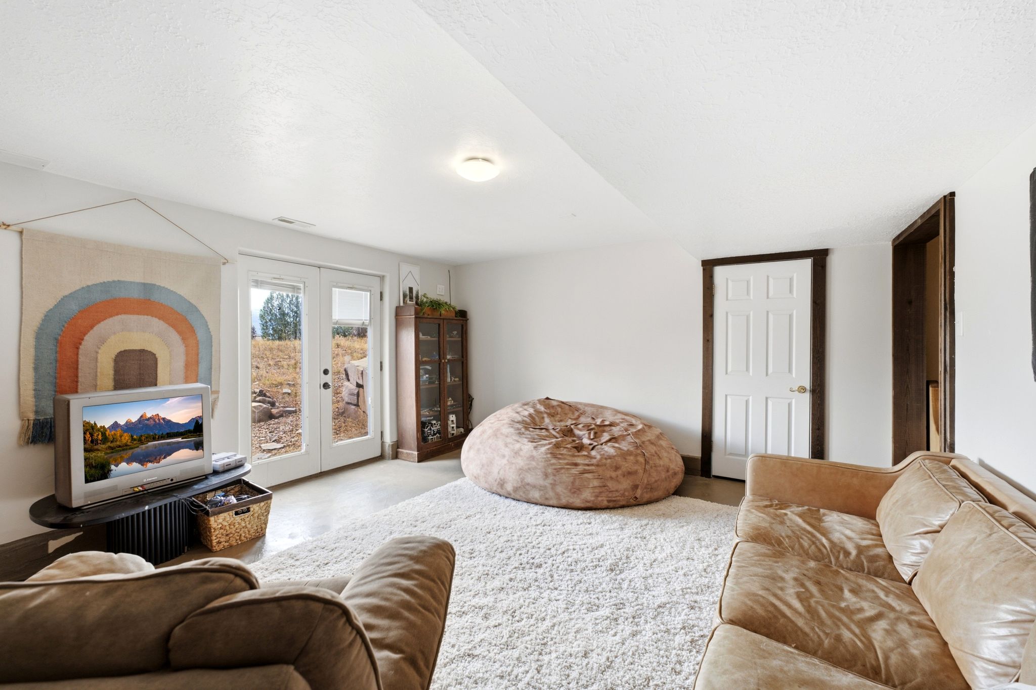 Bright interior room featuring white walls and a light-colored, textured area rug