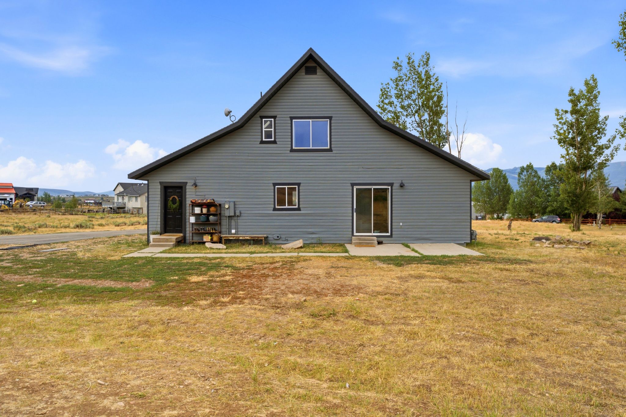 Gray siding exterior with black trim, a gabled roof, and multiple windows