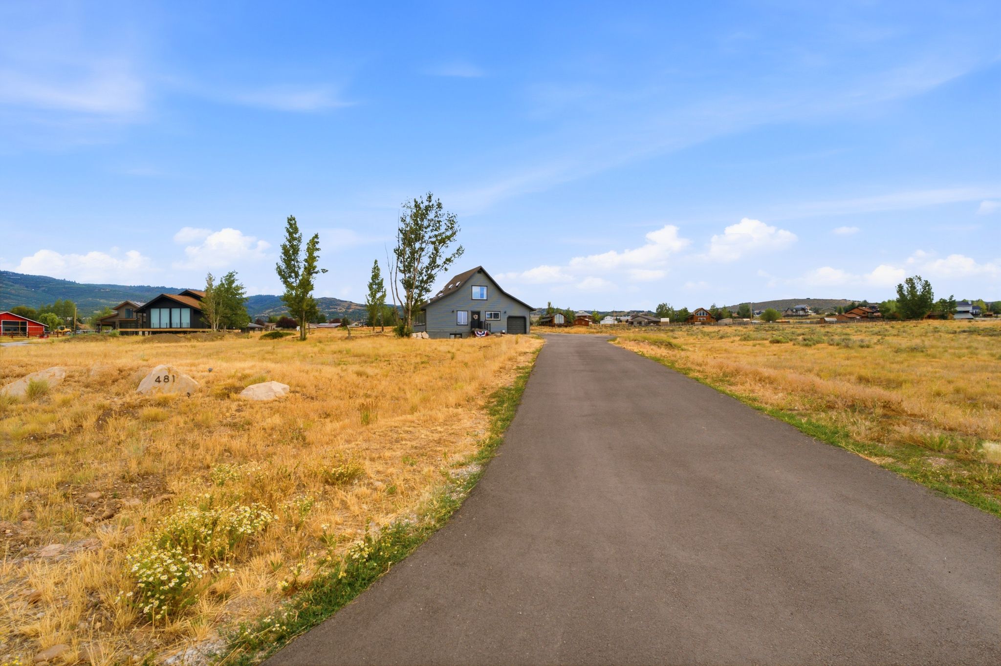 Paved road bordering an expansive land parcel with a distant mountain range