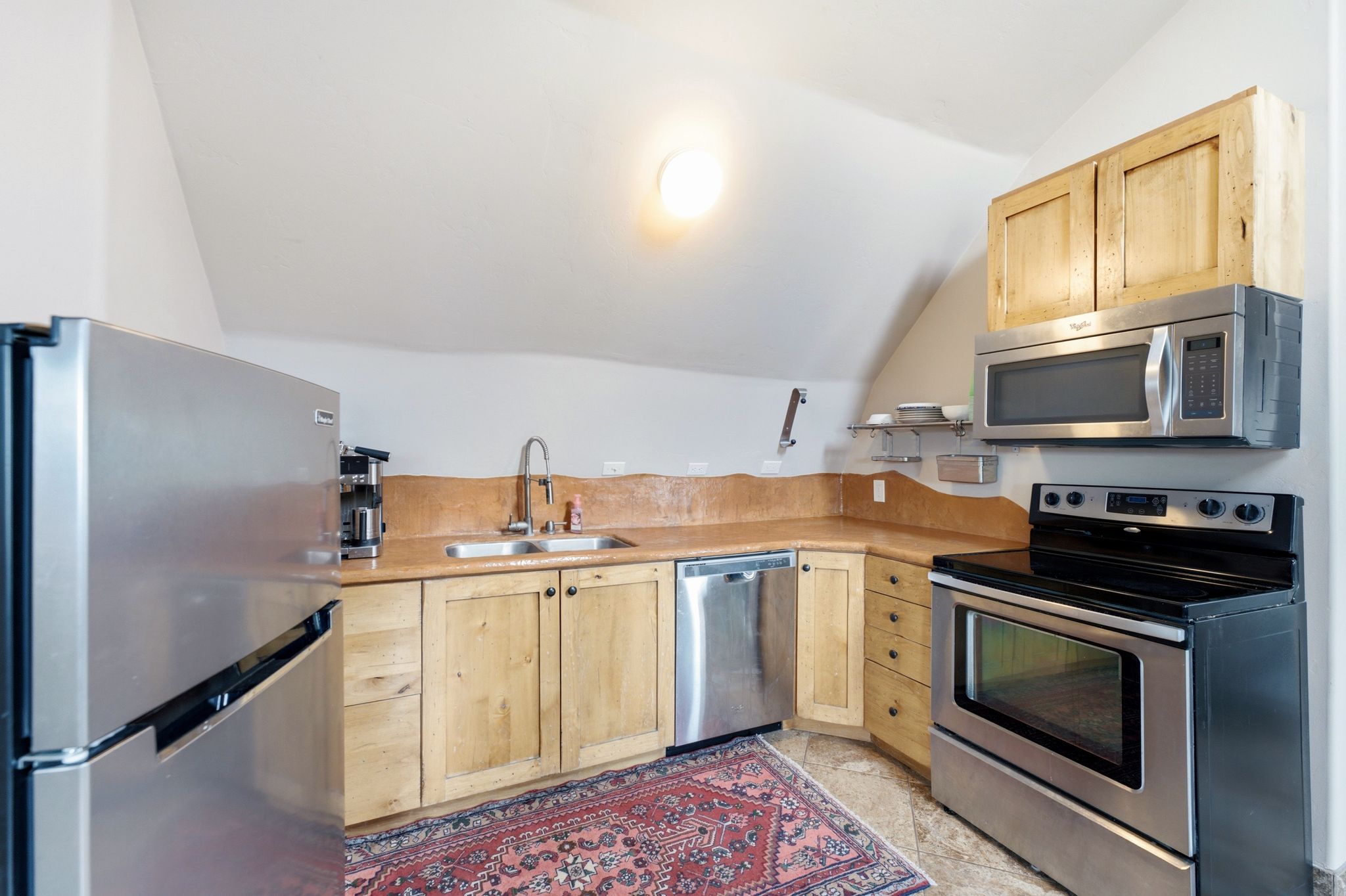 Kitchenette featuring stainless steel appliances, wood cabinetry, and a corner sink