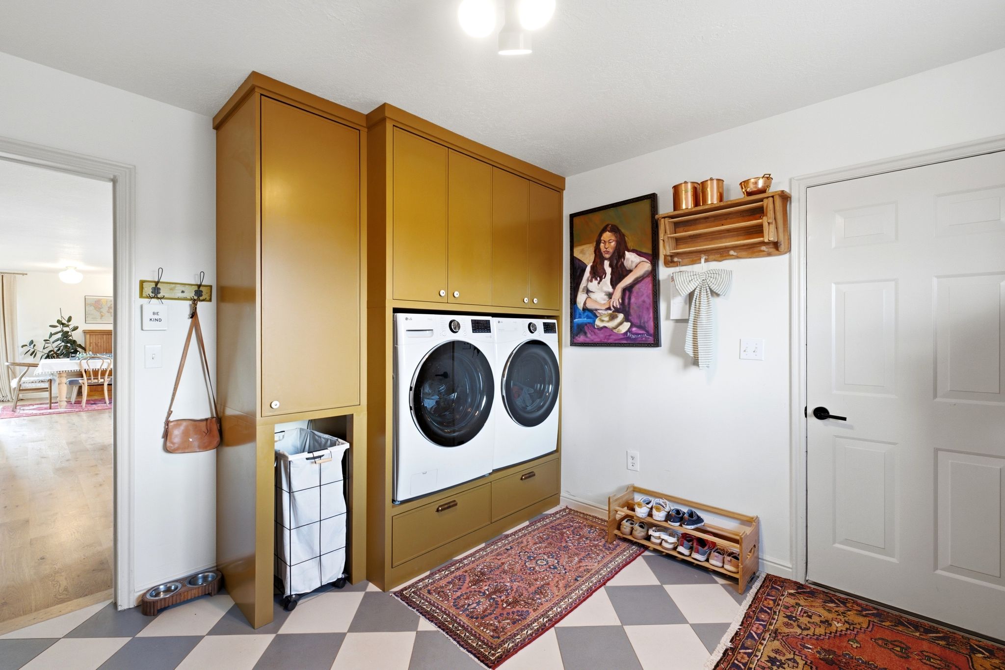 Dedicated laundry area featuring stacked front-load appliances, integrated cabinetry, and checkerboard floor tiling