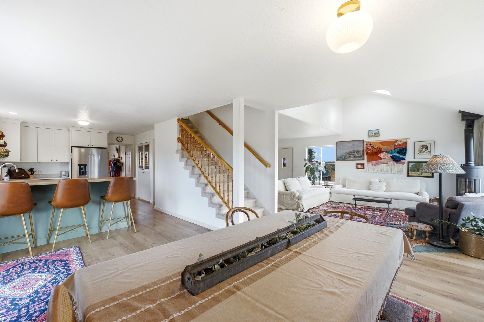 Open-concept living area featuring wood-finish flooring, a contemporary wood-burning stove, and vaulted ceilings