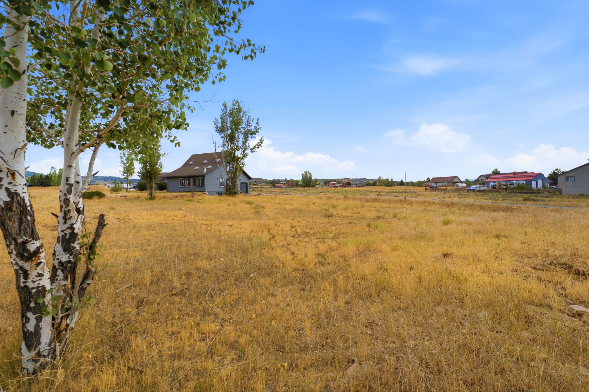 Spacious open lot featuring a scattered tree line and a clear, expansive sky