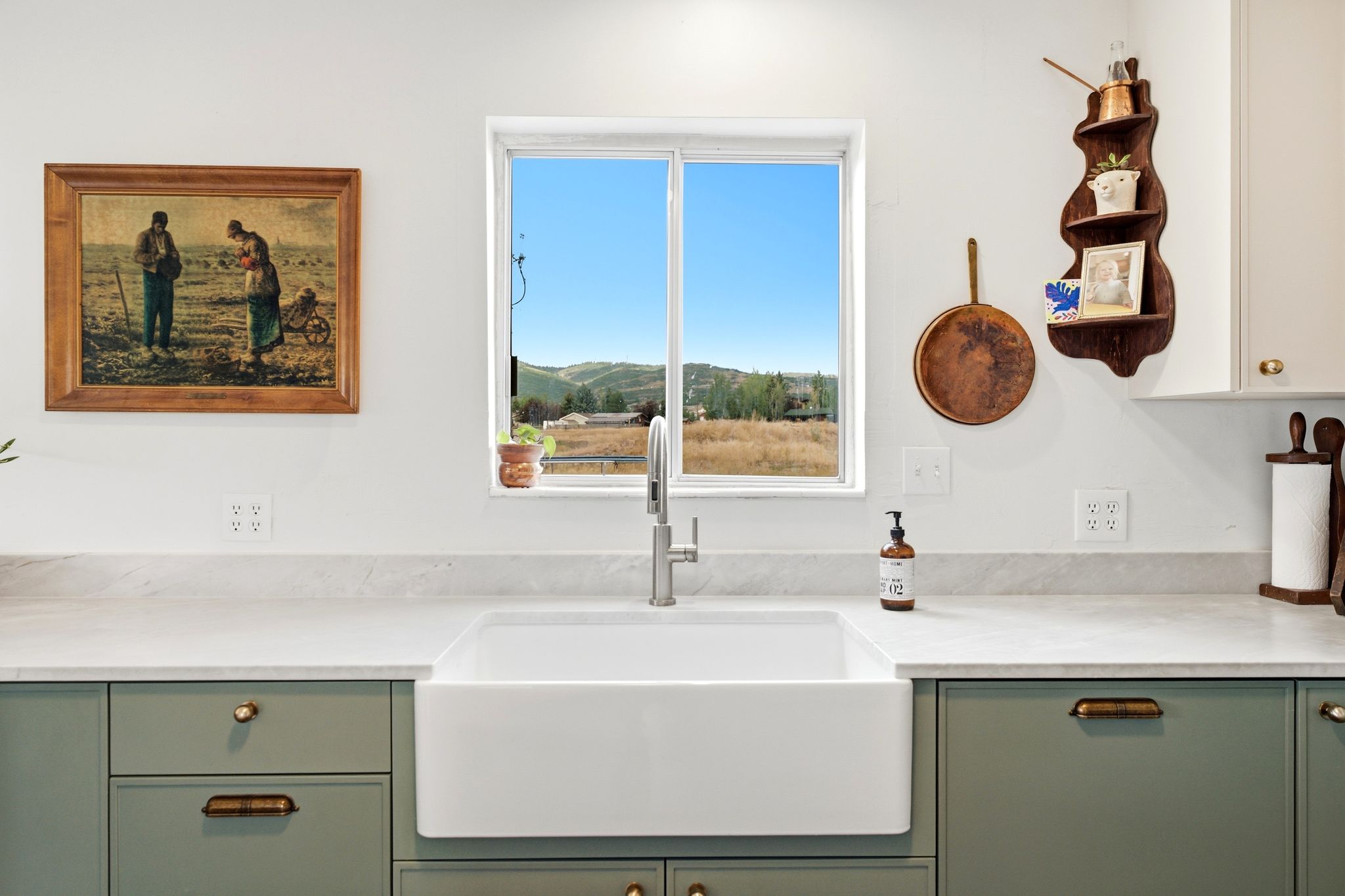 White farmhouse sink with a gooseneck faucet, set within light gray countertops