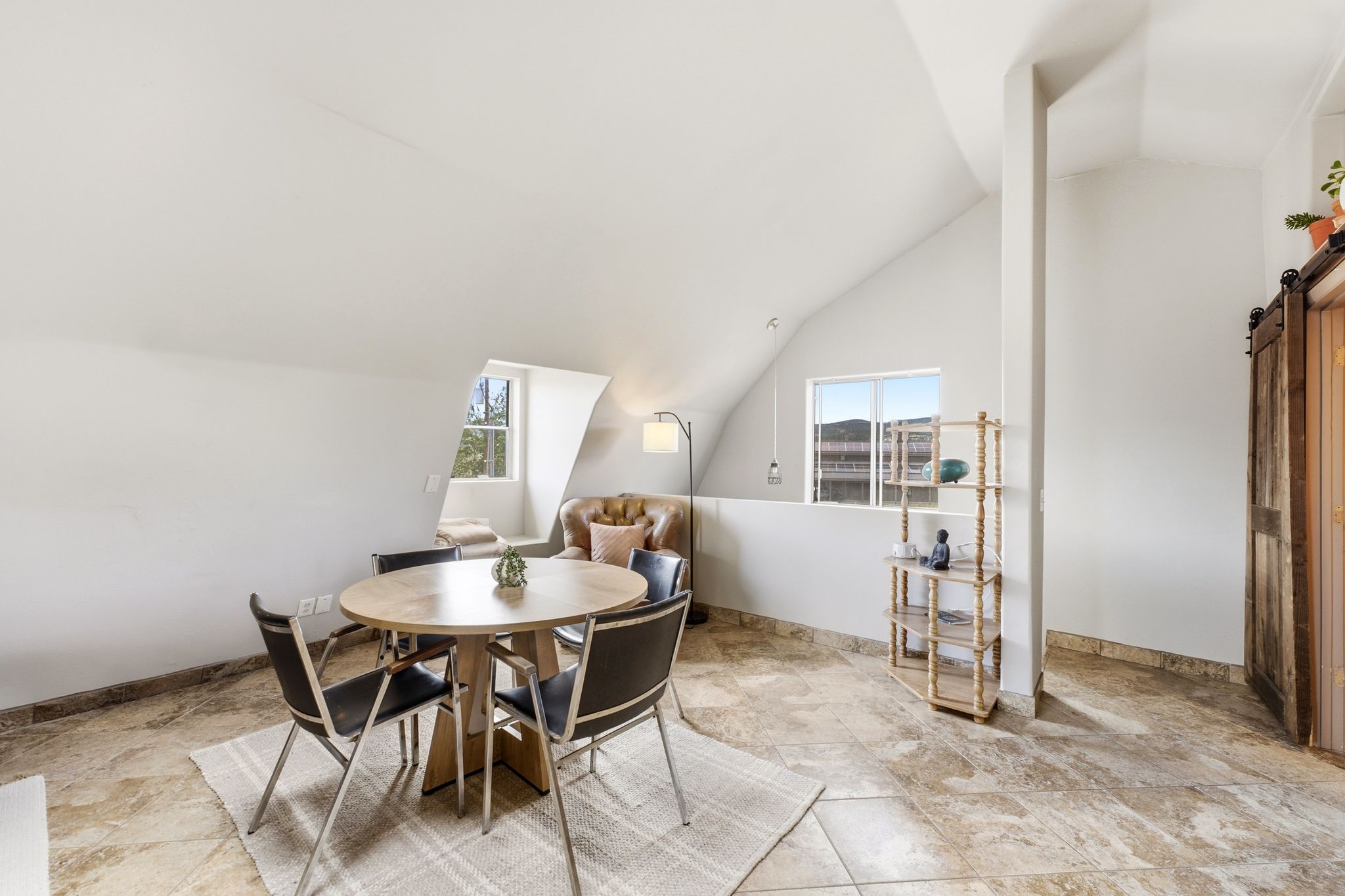 Bright room featuring sloped ceilings, multiple windows, and tile flooring