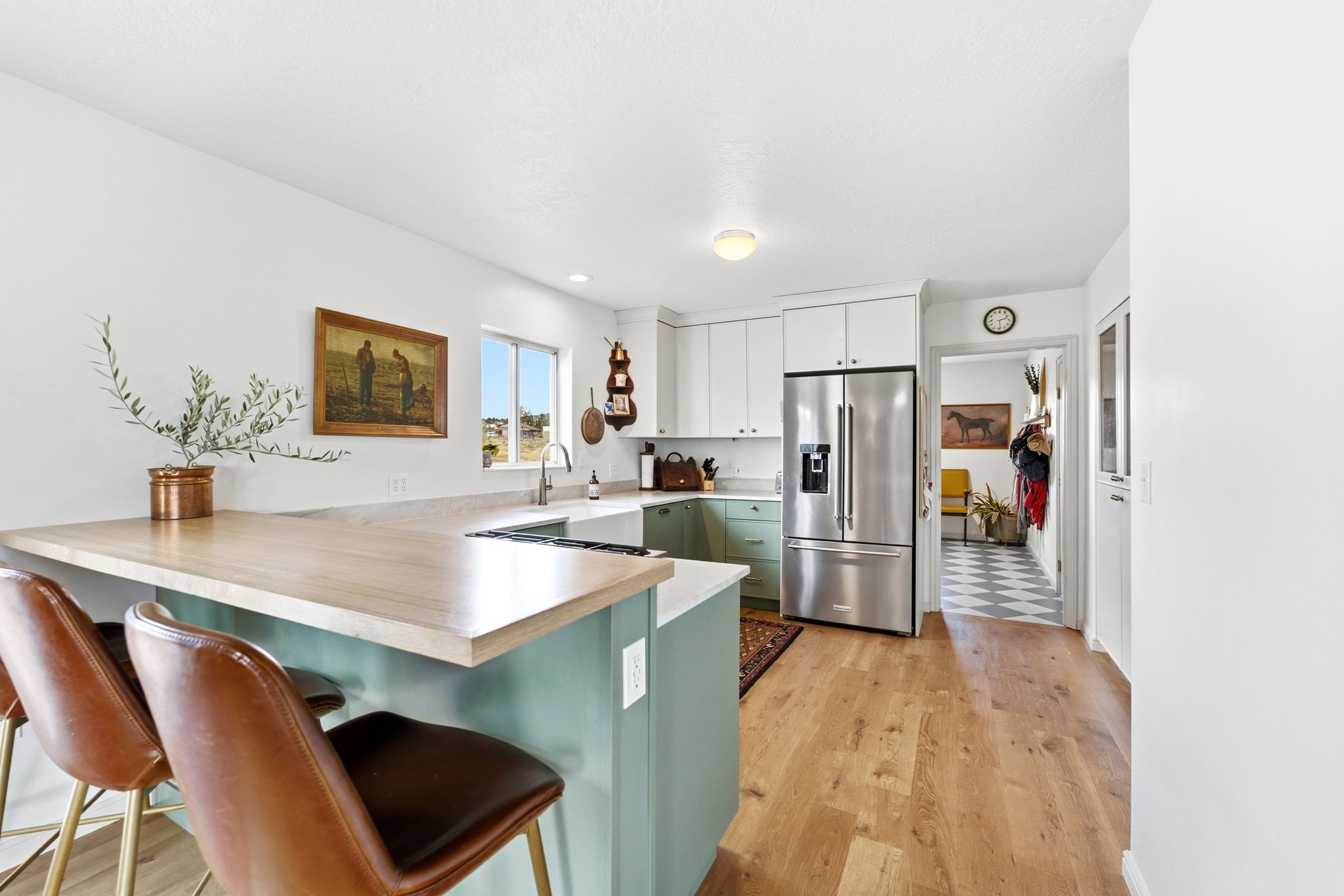 Modern kitchen featuring a wood-finish peninsula countertop, light-toned cabinetry, stainless steel refrigerator, and wood-finish flooring
