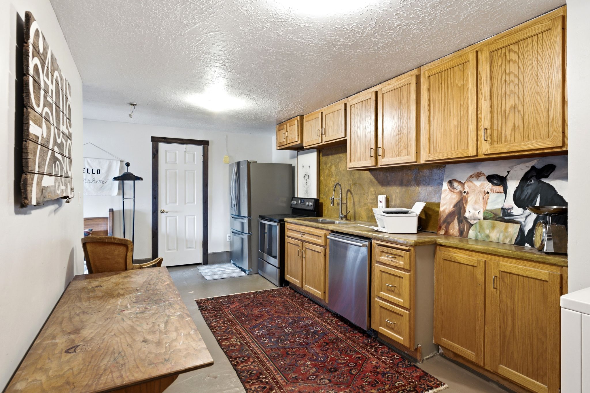 Kitchenette with oak cabinetry, stone-finish countertops, and stainless steel appliances including a refrigerator, range, and dishwasher