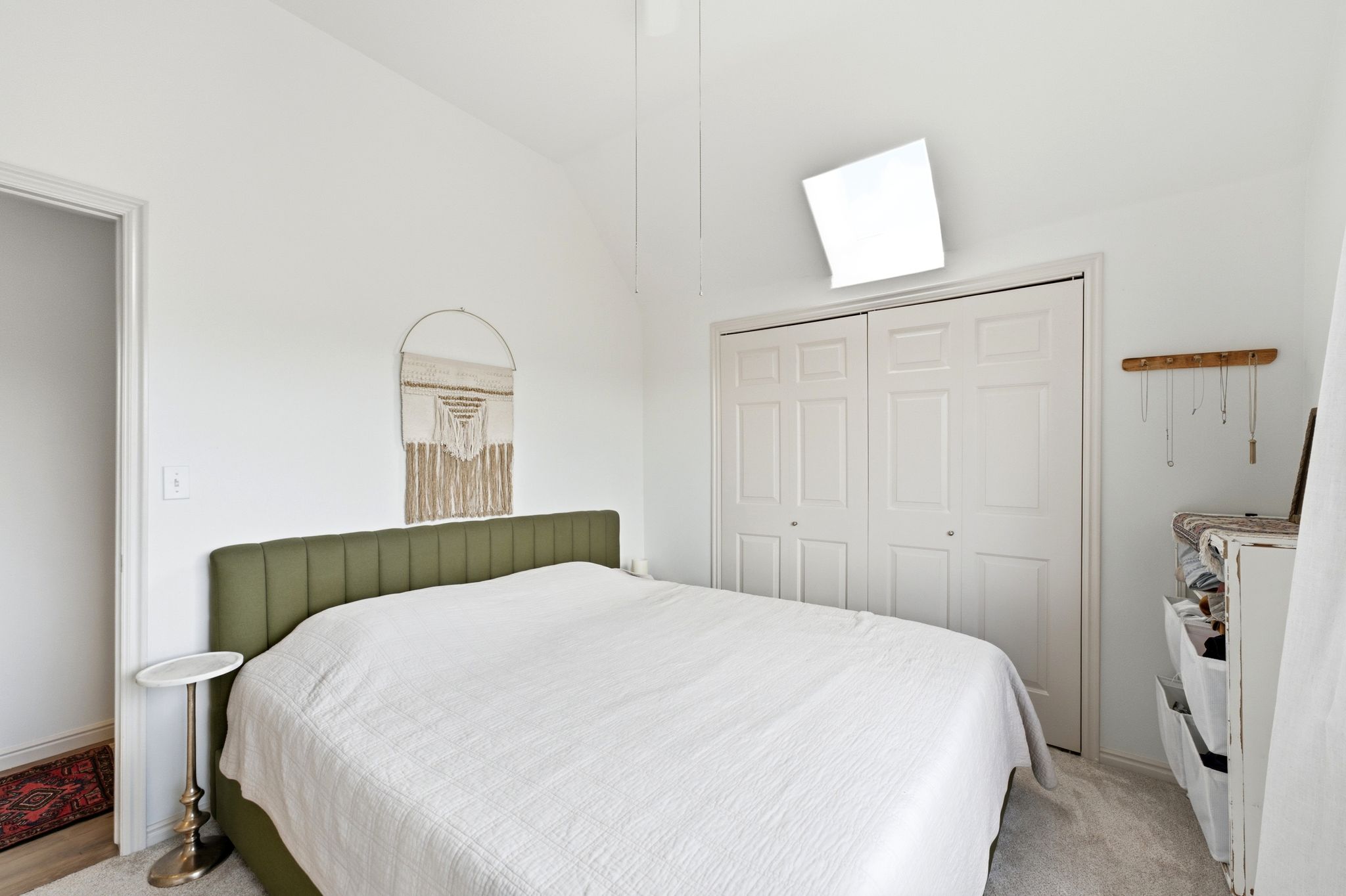 Vaulted ceiling bedroom with light-colored carpeting, white walls, and a bi-fold closet with paneled doors