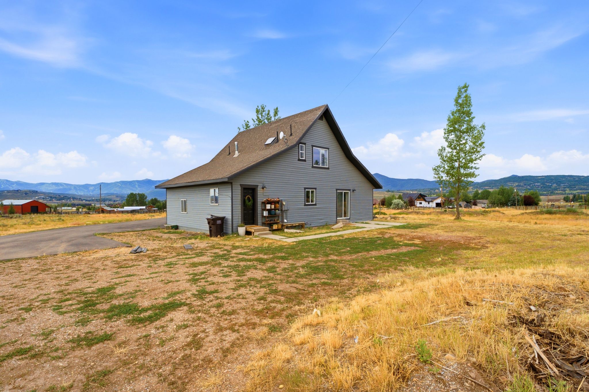 Gray siding exterior with multiple windows, a gabled roof, and a front entry