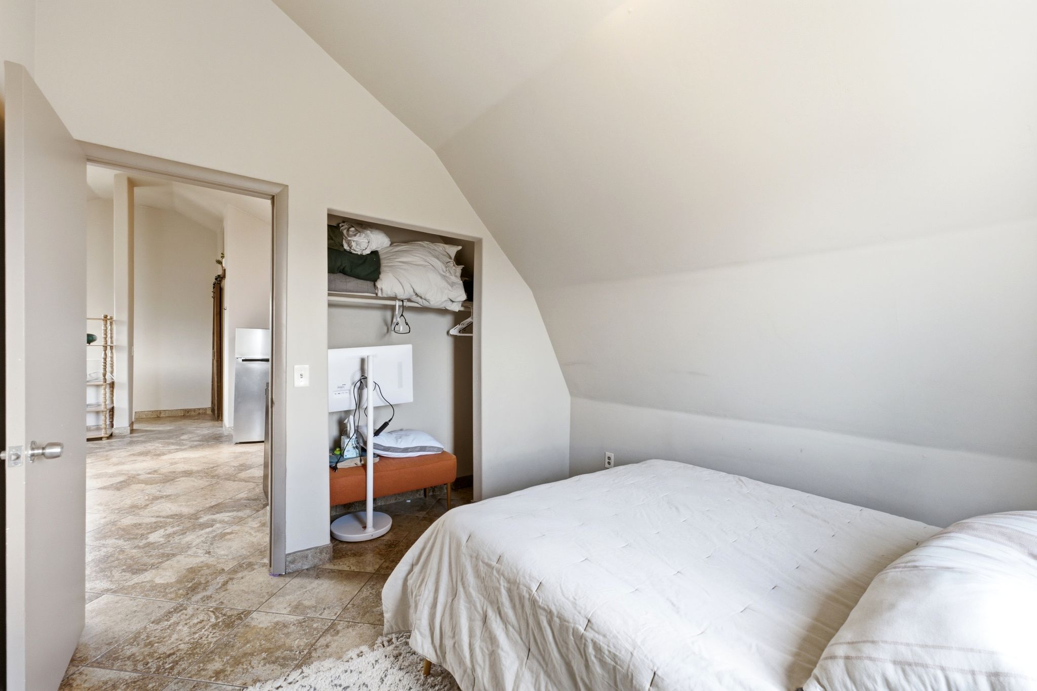 Bedroom featuring an angled ceiling, an open closet with built-in shelving, and light-toned wall paint