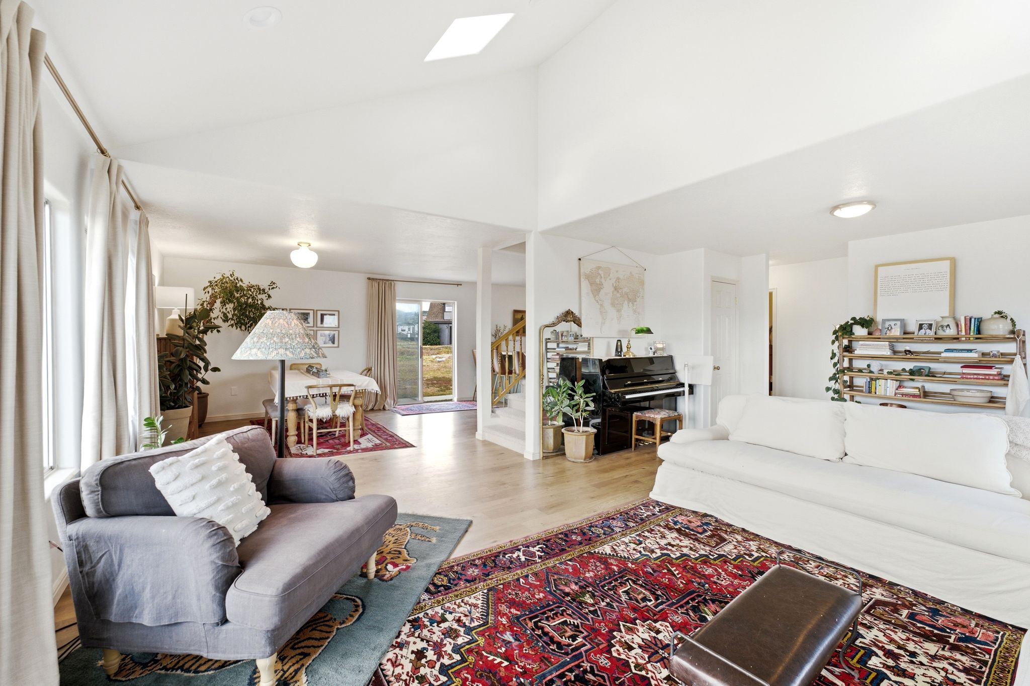 Vaulted ceilings with a skylight, light wood-finish flooring, and bright white walls create an open atmosphere